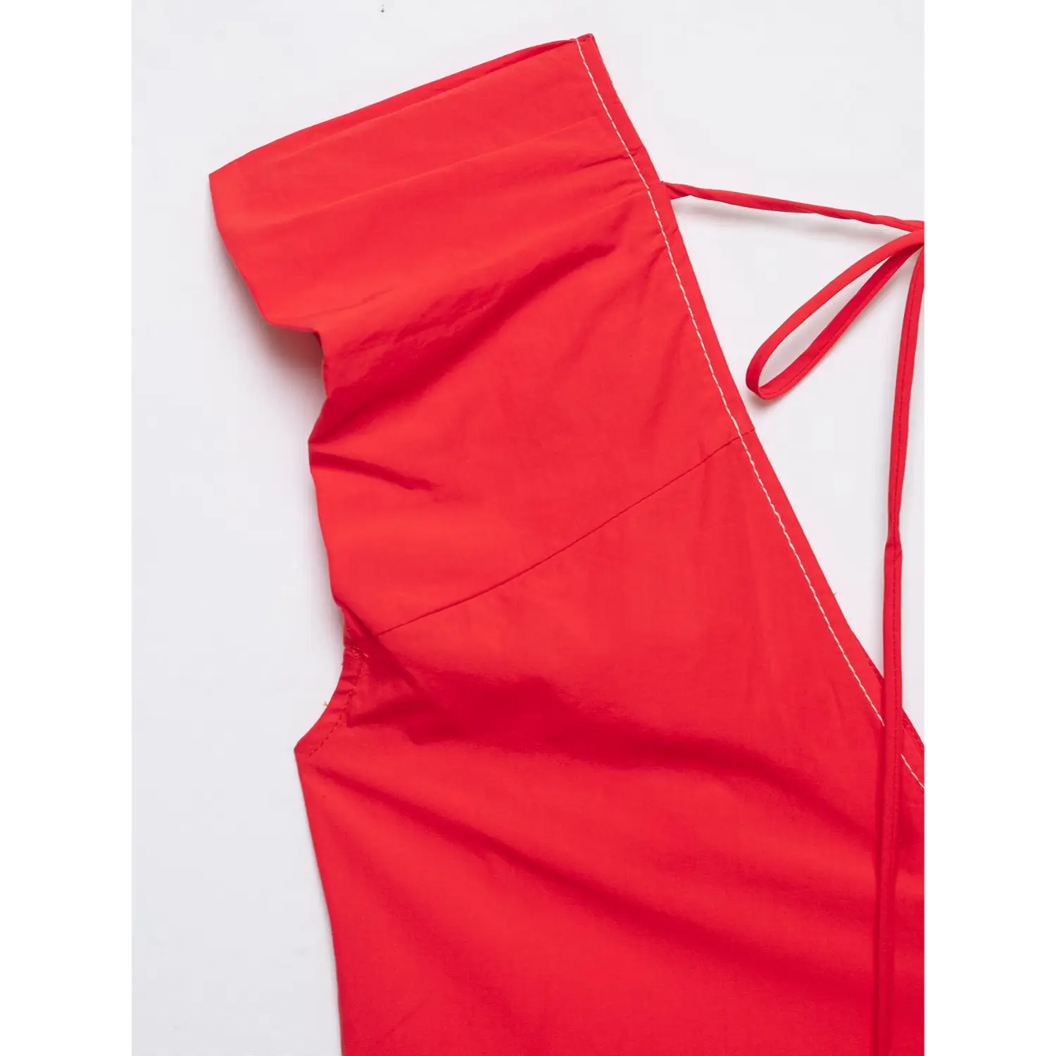 Close up of ruffle cap sleeve and contrast stitching on red tie back blouse