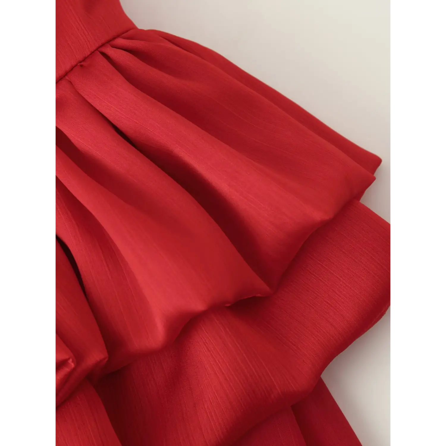 Macro shot of gathered tiered ruffle waist on bright red sheer chiffon maxi skirt