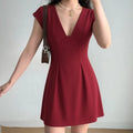 Model wearing a red V-neck cap sleeve mini dress, featuring a structured bodice, fitted waist, and flared skirt.