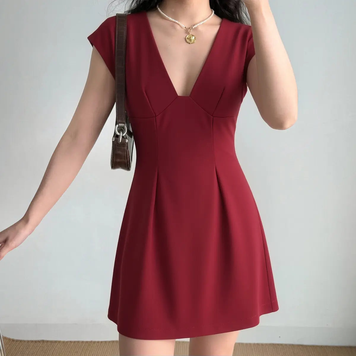 Model wearing a red V-neck cap sleeve mini dress, featuring a structured bodice, fitted waist, and flared skirt.