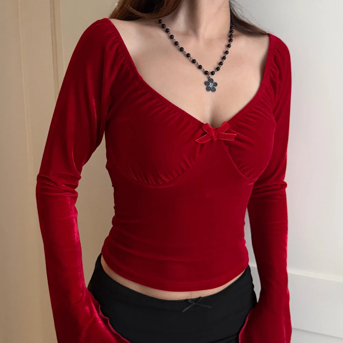 Model wearing red velvet sweetheart bow long sleeve crop top, indoor three quarter view