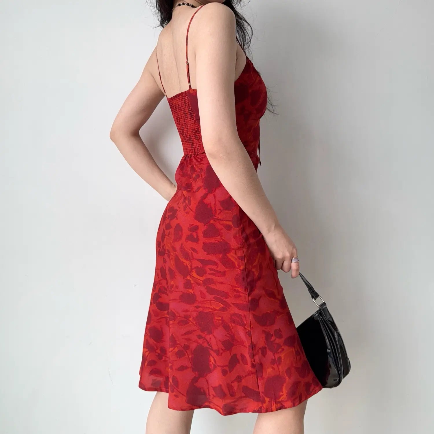 Back three-quarter shot highlighting full elastic smocked back panel, adjustable thin straps and flared midi hem