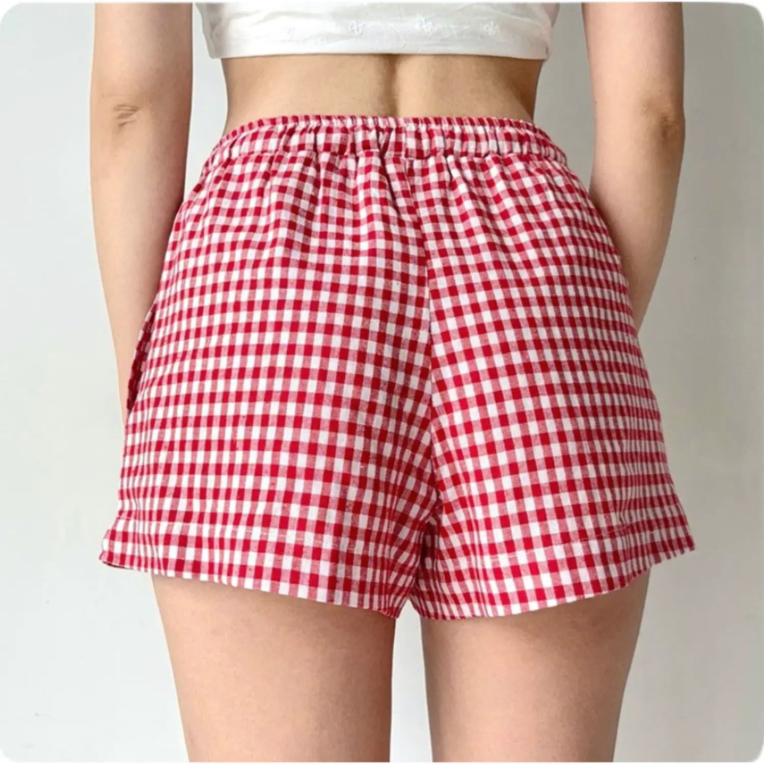 Back view of red and white gingham shorts, worn with a white cropped top