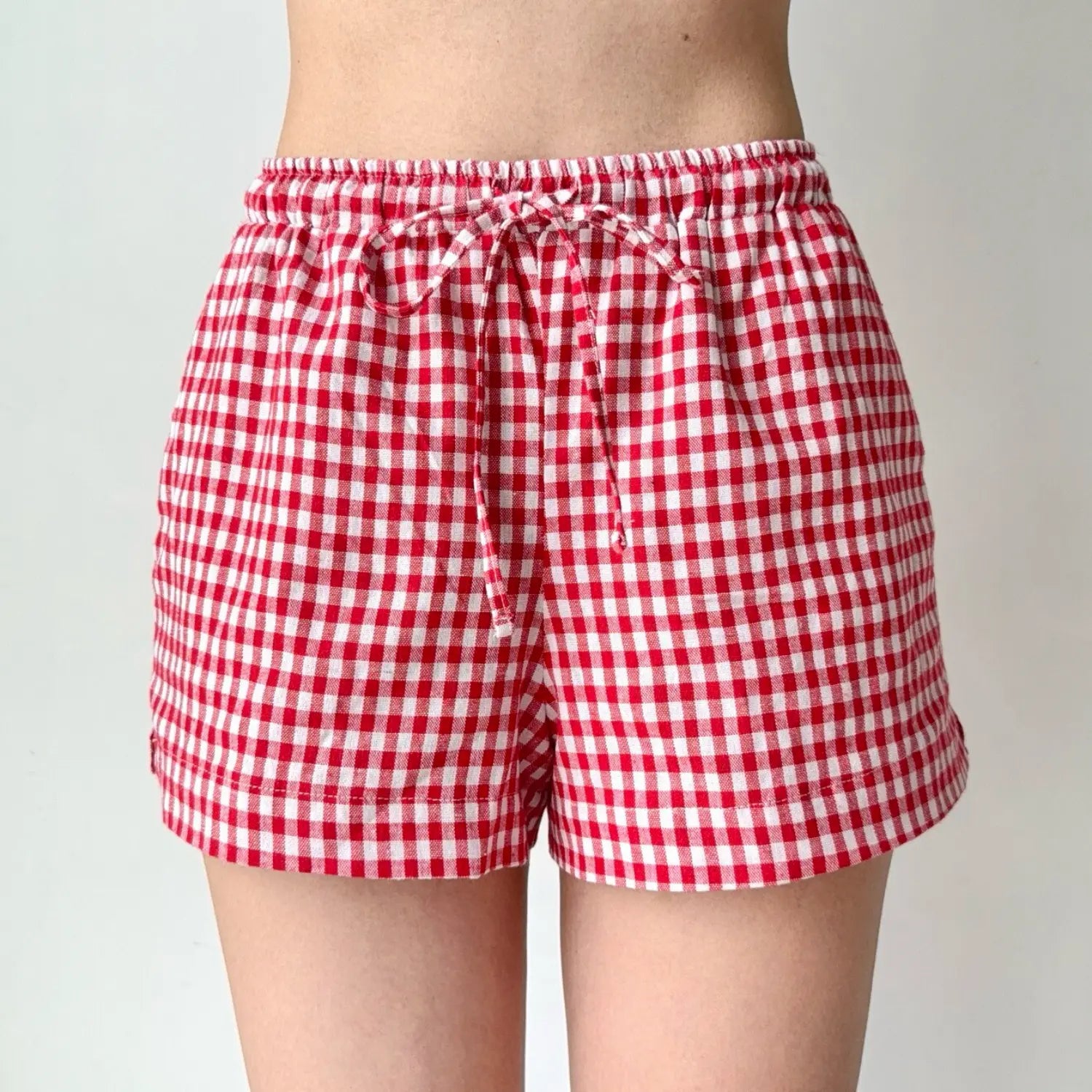 Close-up shot of red and white gingham shorts, showing the drawstring tie and fabric texture