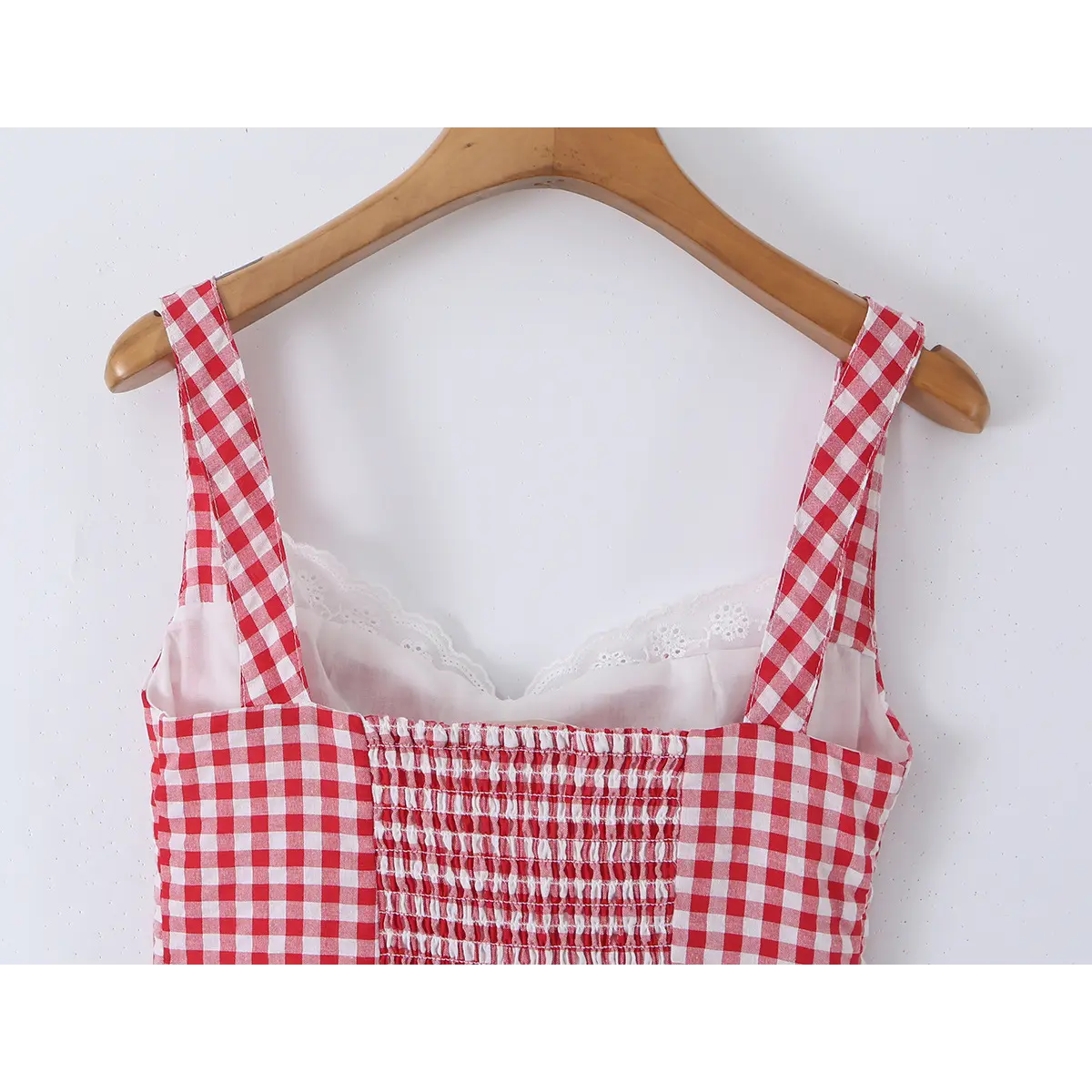Close-up detail of the back of a red and white gingham bustier tank top, showing the lace-trimmed inner layer and smocked panel.