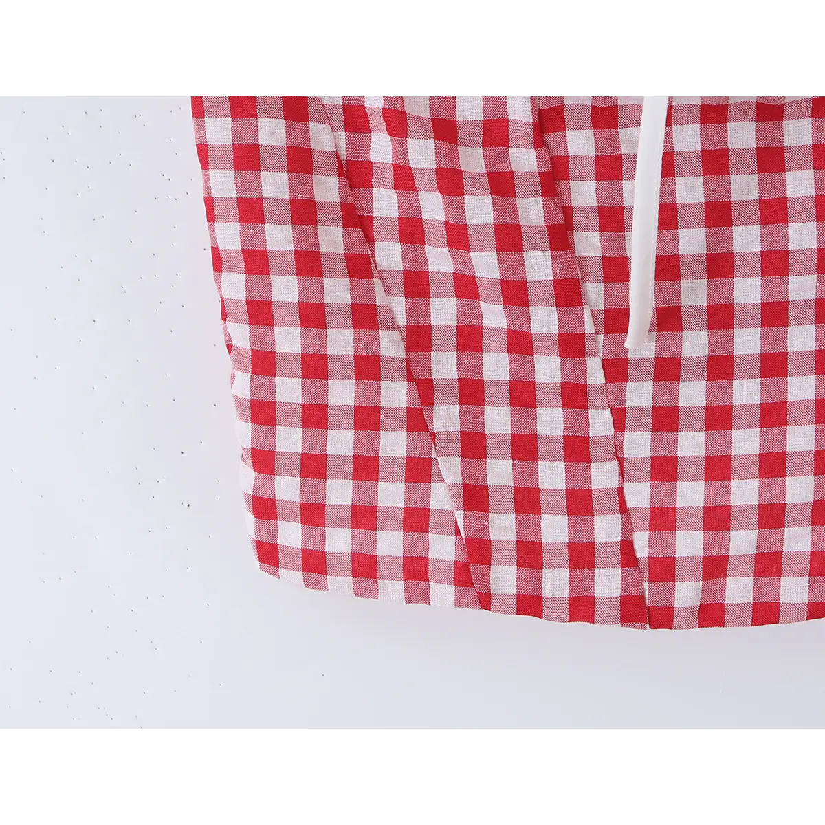 Close-up detail of the hem on a red and white gingham bustier tank top, showing the fabric pattern and vertical seams.