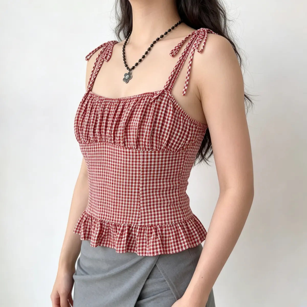 Three-quarter view of the red and white gingham cami top, paired with a gray skirt.