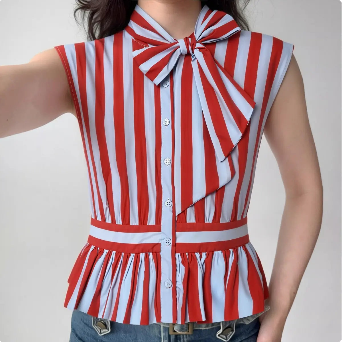 The top styled on a model, highlighting the fit, bow detail, and peplum silhouette.