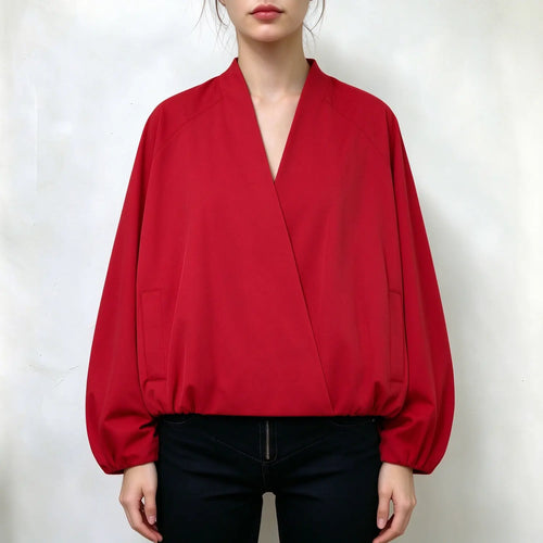 Model wearing solid red bomber jacket, deep V wrap front, raglan bishop sleeves, side patch pockets, elastic hem and cuffs, relaxed loose silhouette, paired with black jeans, plain white background