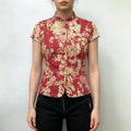 Model wearing red chinese floral print cap‑sleeve mandarin collar fitted jacket, styled with black pants, front lifestyle shot