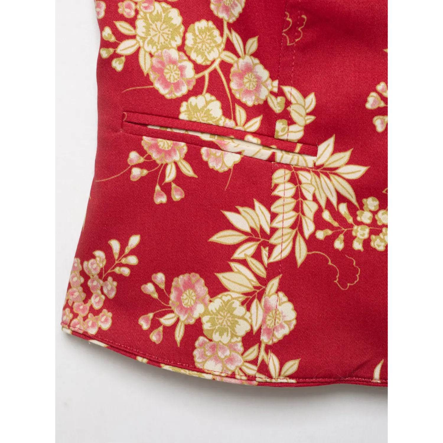 Macro close‑up of side pocket stitching and bottom hem on red oriental floral print jacket