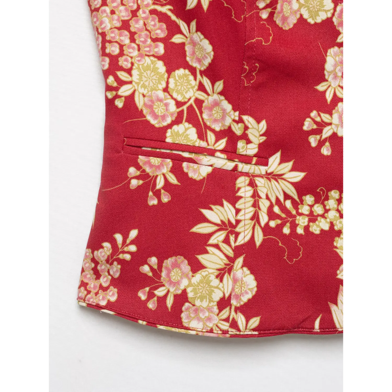 Close‑up detail of slash side pocket and finished hem on red chinese floral print tailored jacket