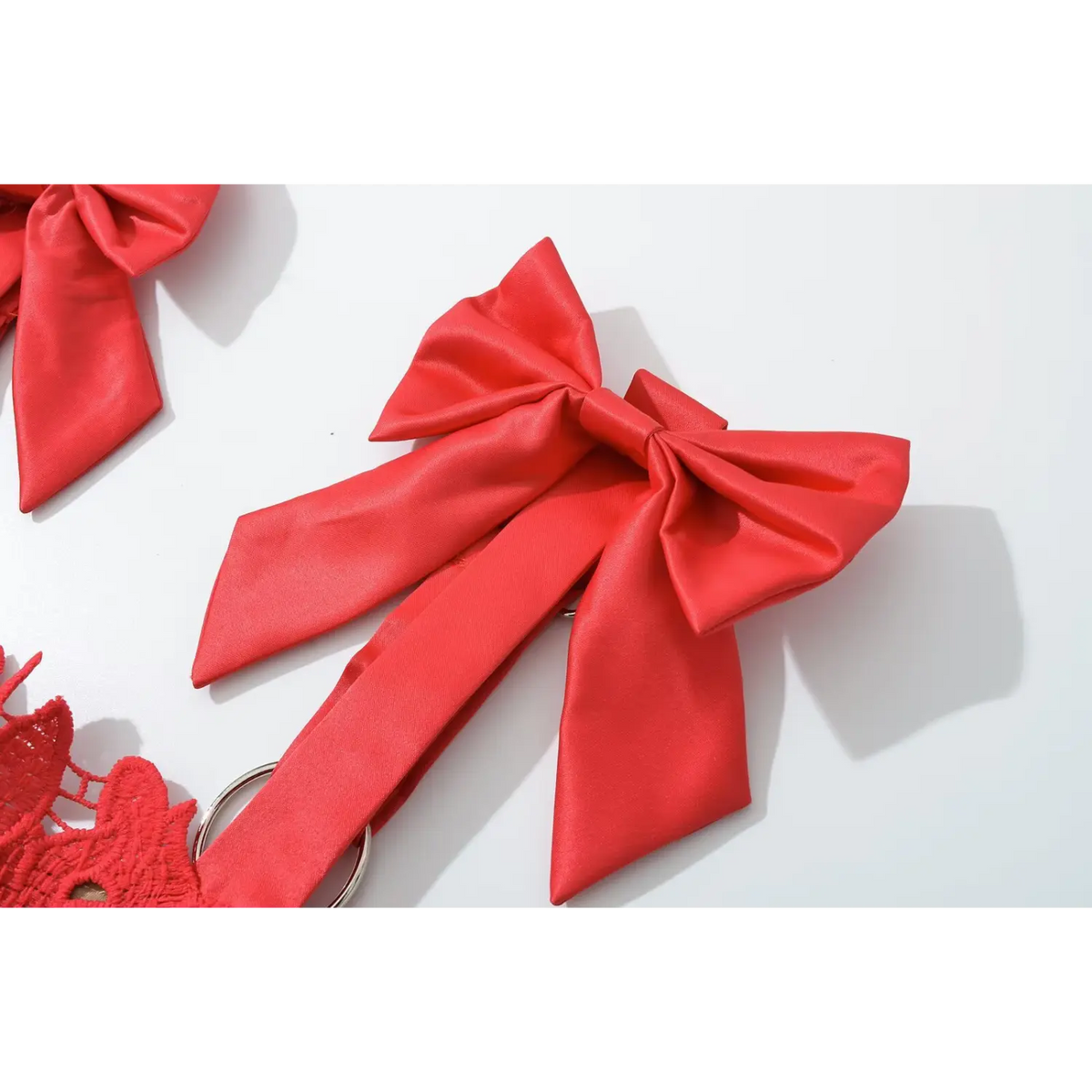 Macro close‑up of glossy red satin shoulder bow accessory