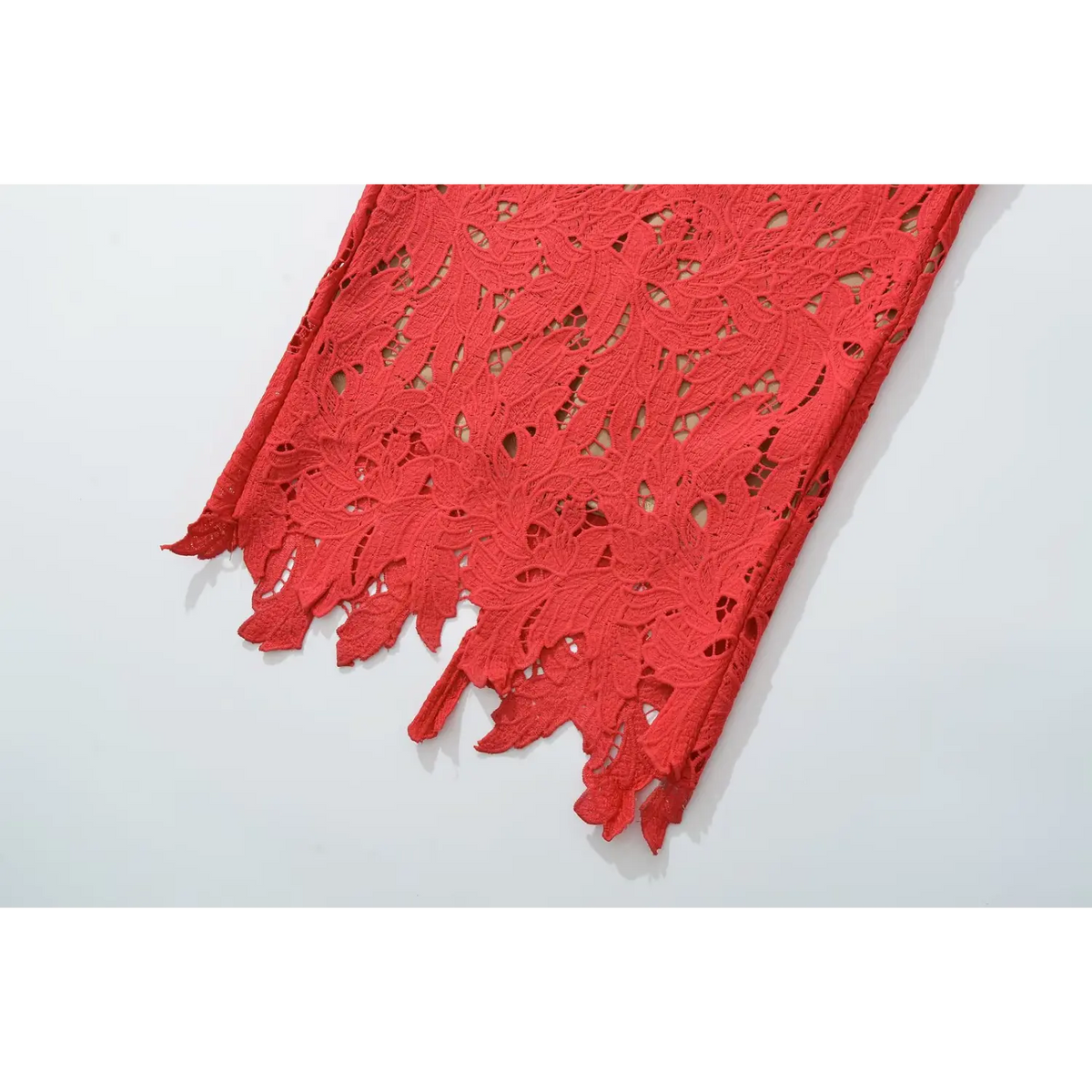 Close‑up of scalloped raw edge hem on red lace maxi dress