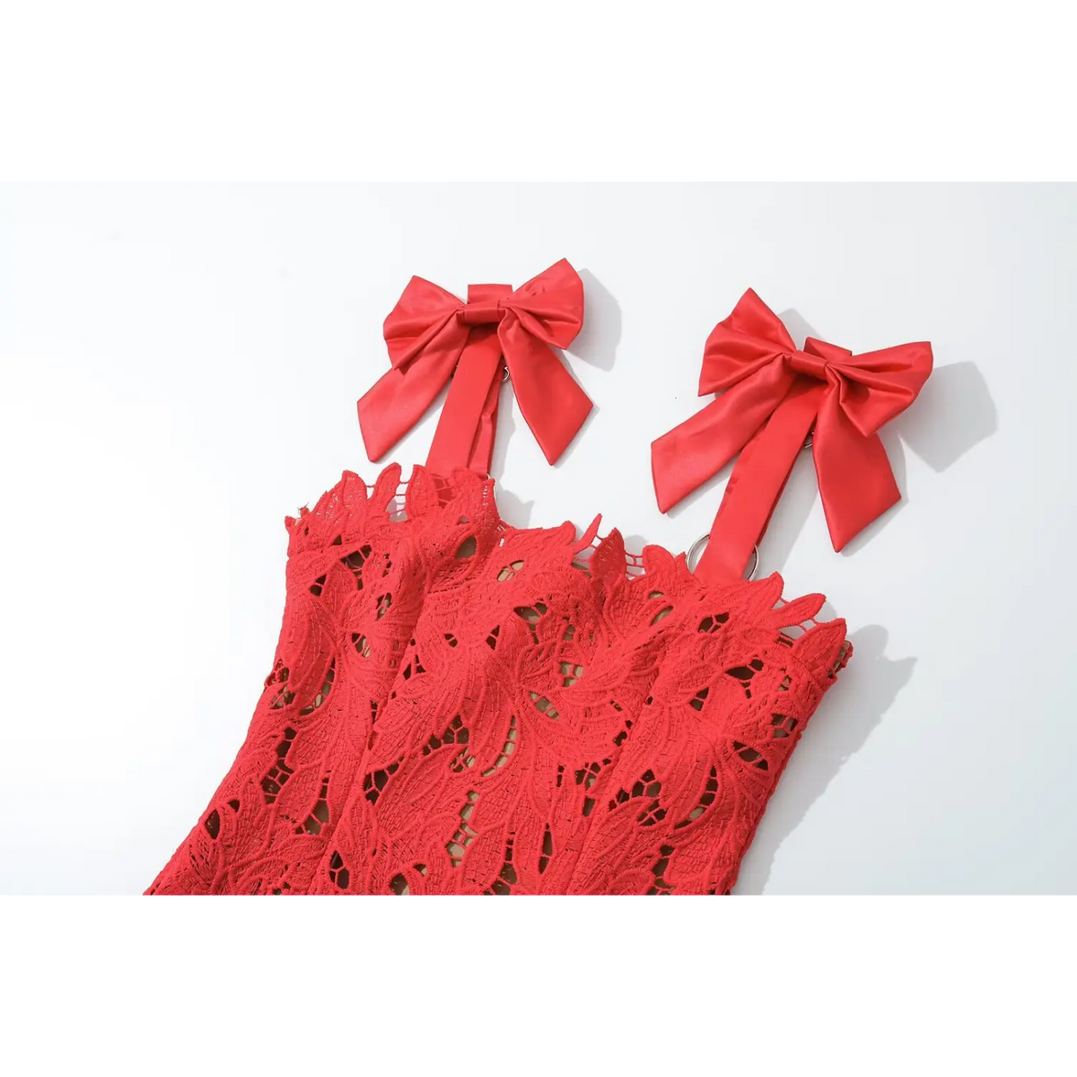 Close‑up of red satin bow shoulder straps on red lace maxi dress