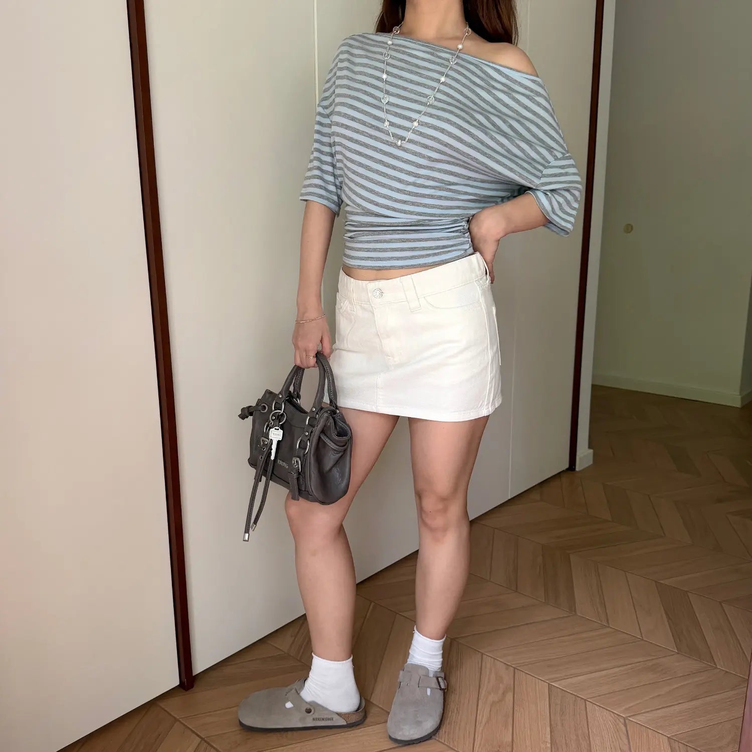 Full length indoor shot of casual coordinate, striped off shoulder cropped tee + white denim skirt, daily streetwear look