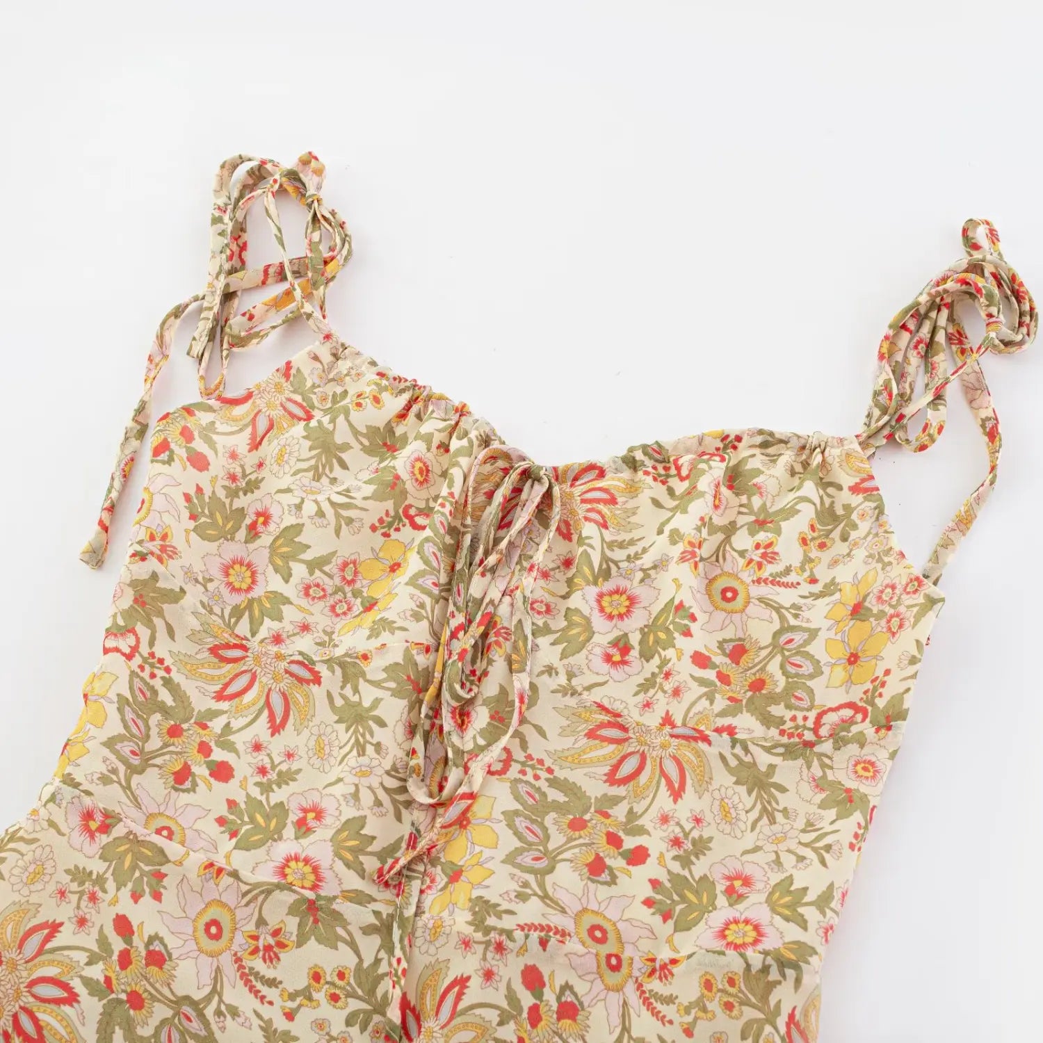 Full flat lay shot of vintage floral spaghetti strap mini dress, self-fabric tie adjustable shoulder straps, front bust drawstring ruched detail on cream chiffon base