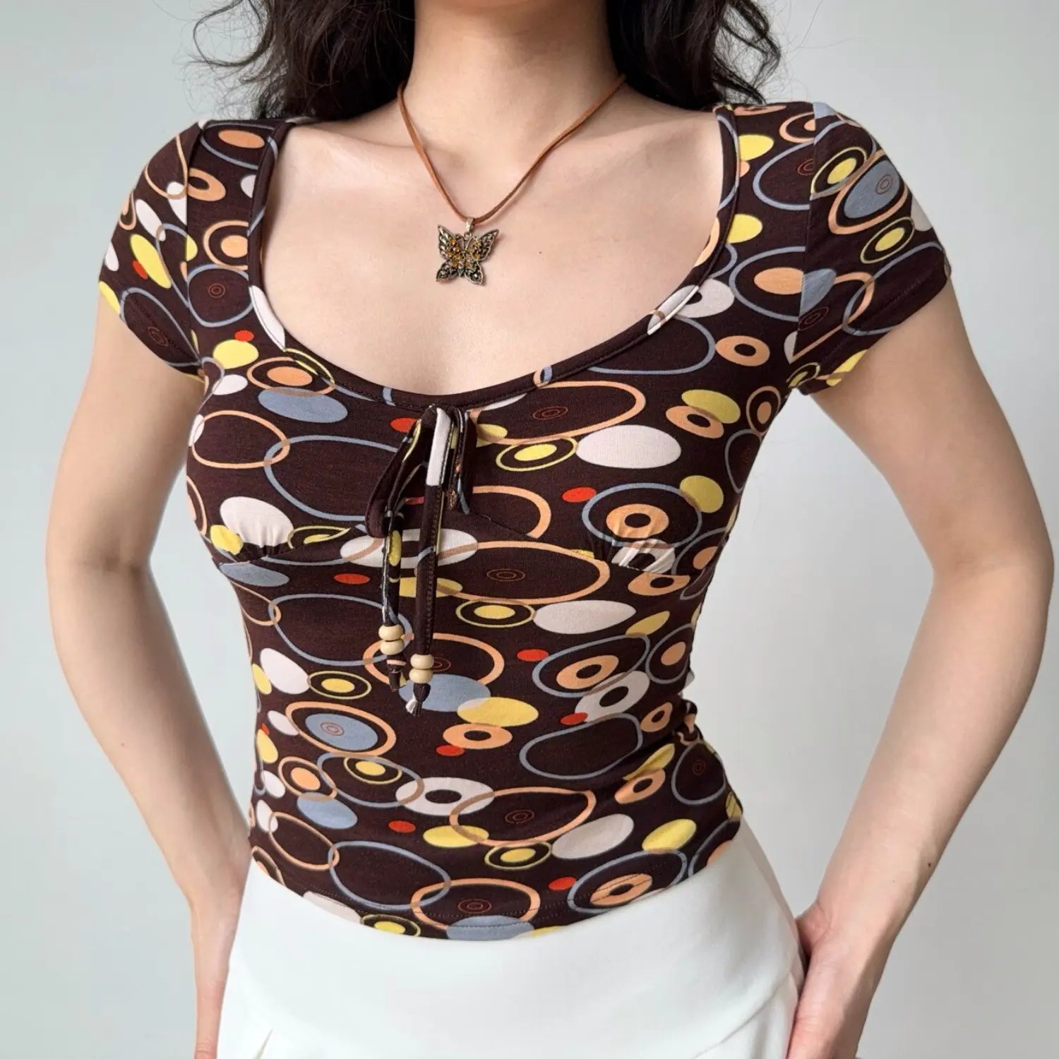 Side back view of vintage brown geometric circle print fitted crop t shirt, short cap sleeve stretch knit fabric y2k top
