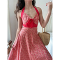 Close front lifestyle shot of vintage cherry floral halter maxi dress paired with rattan woven handbag, classic picnic summer outfit.