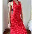 Close front indoor lifestyle picture of red polka dot chiffon halter gown, bust ruched detail and 3D rose decor, elegant bodycon midi silhouette.
