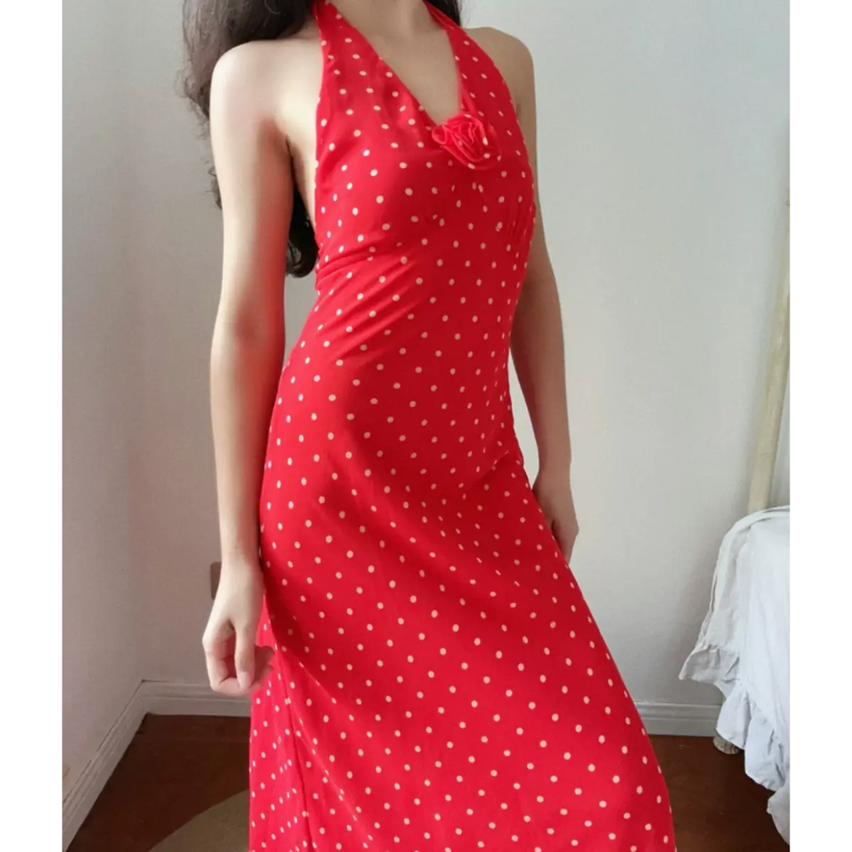 Close front indoor lifestyle picture of red polka dot chiffon halter gown, bust ruched detail and 3D rose decor, elegant bodycon midi silhouette.
