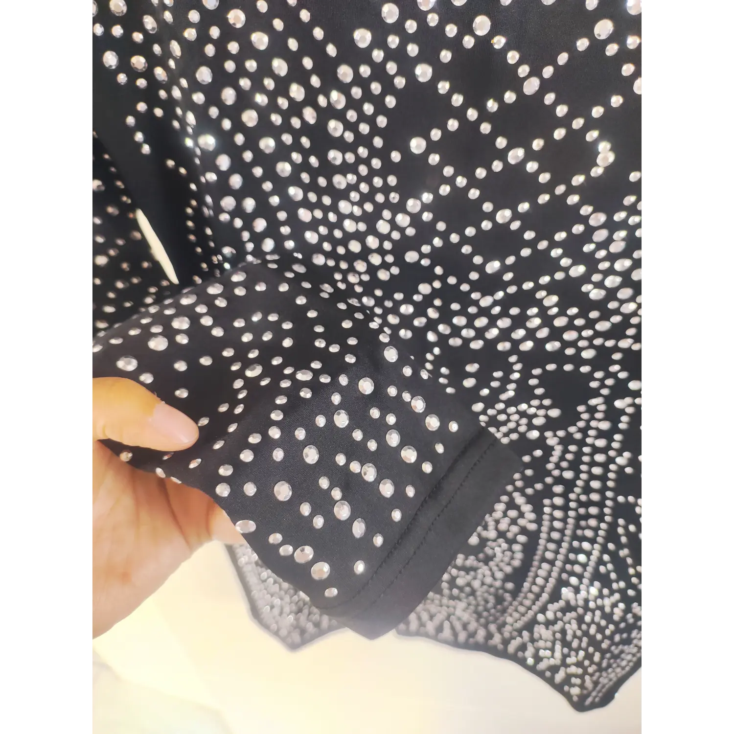 Fabric close-up of long sleeve cuff, mixed size silver hot rhinestones on black stretch fabric