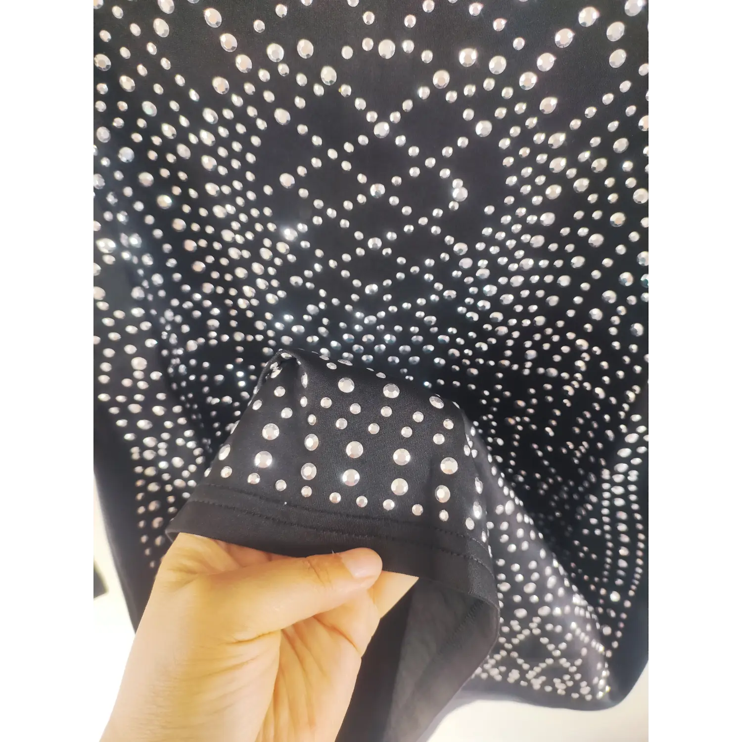 Macro close-up, silver rhinestone embellishment on black fabric sleeve hem