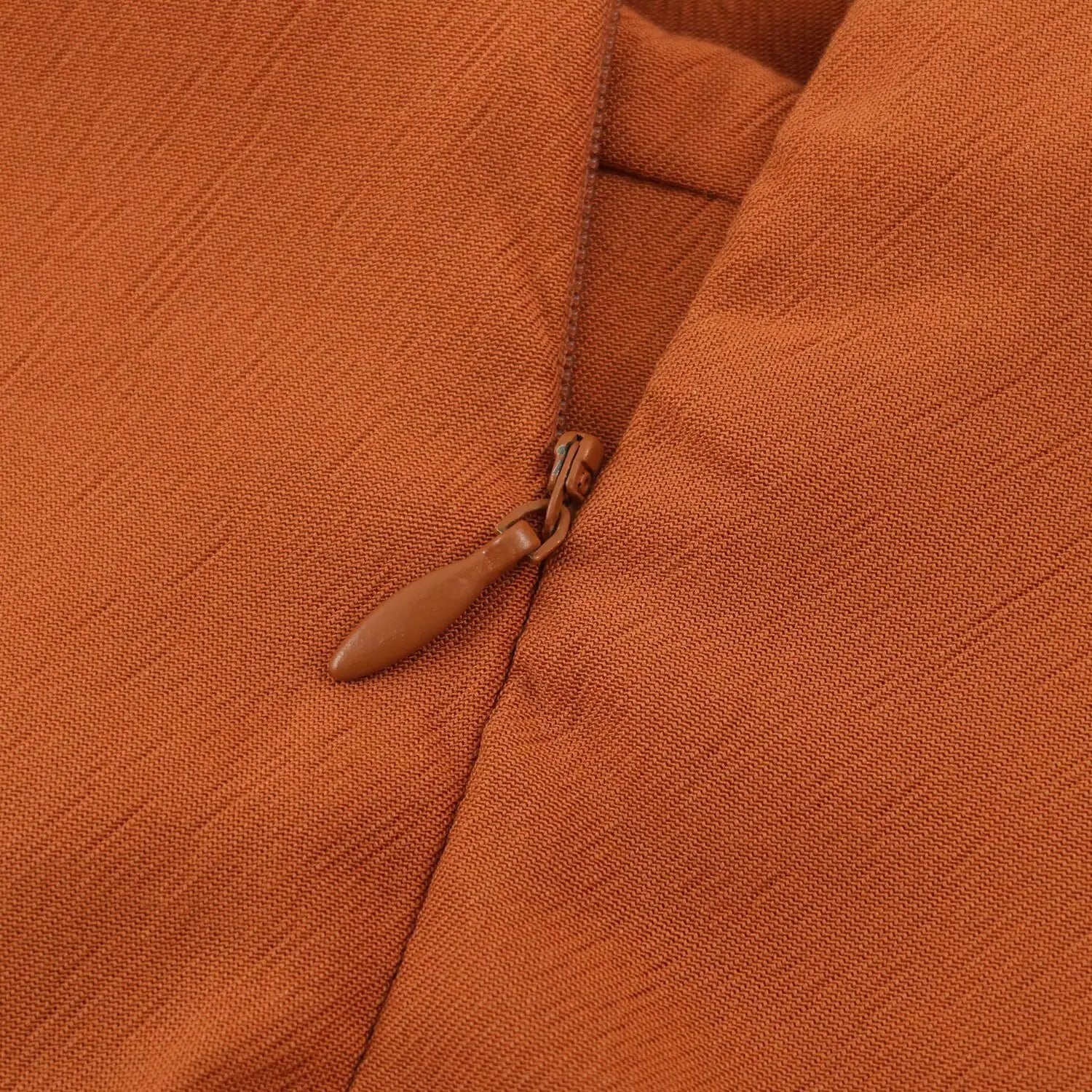 Close-up of matching color invisible zipper pull at back neck for rust sleeveless playsuit