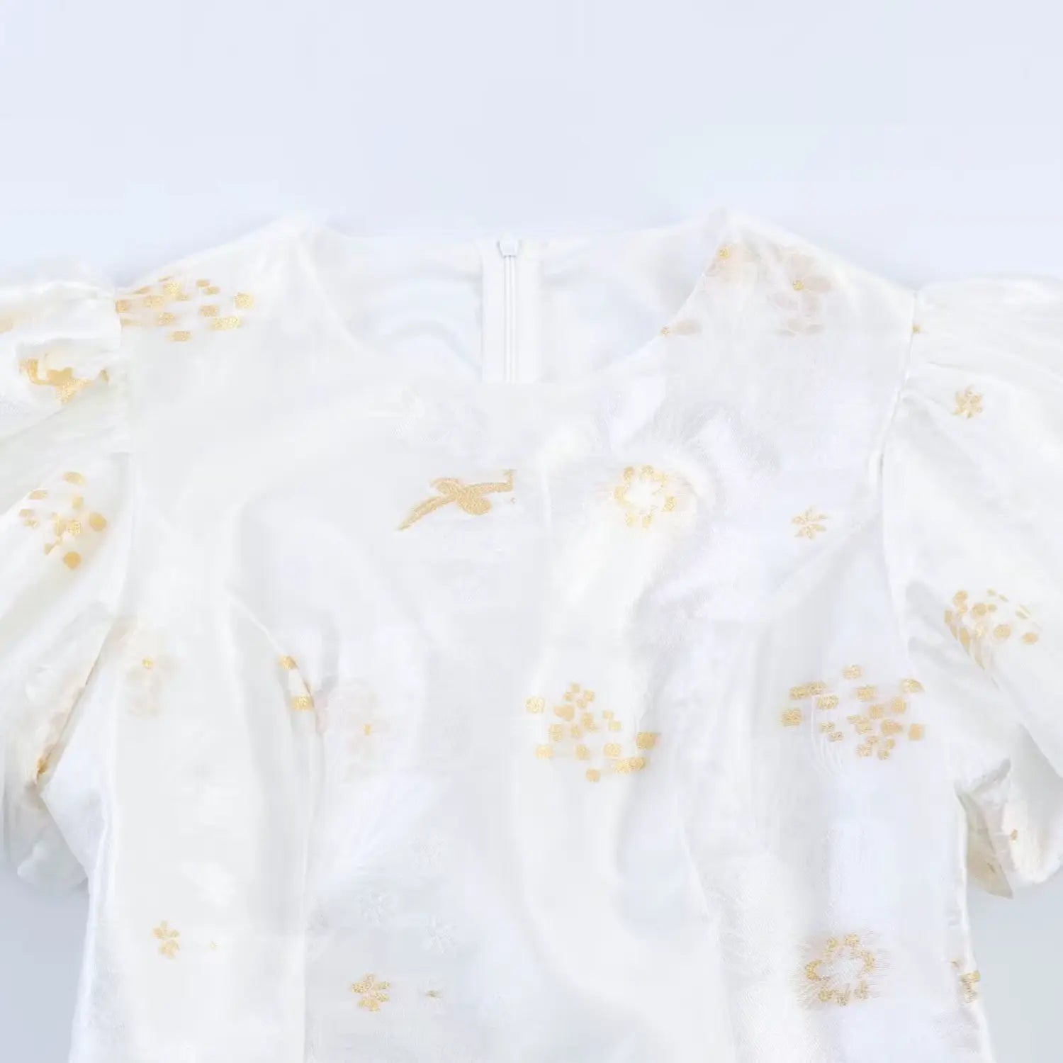 Round neckline partial macro shot, white hidden back zipper pull tab, golden bird and flower embroidery on textured jacquard fabric
