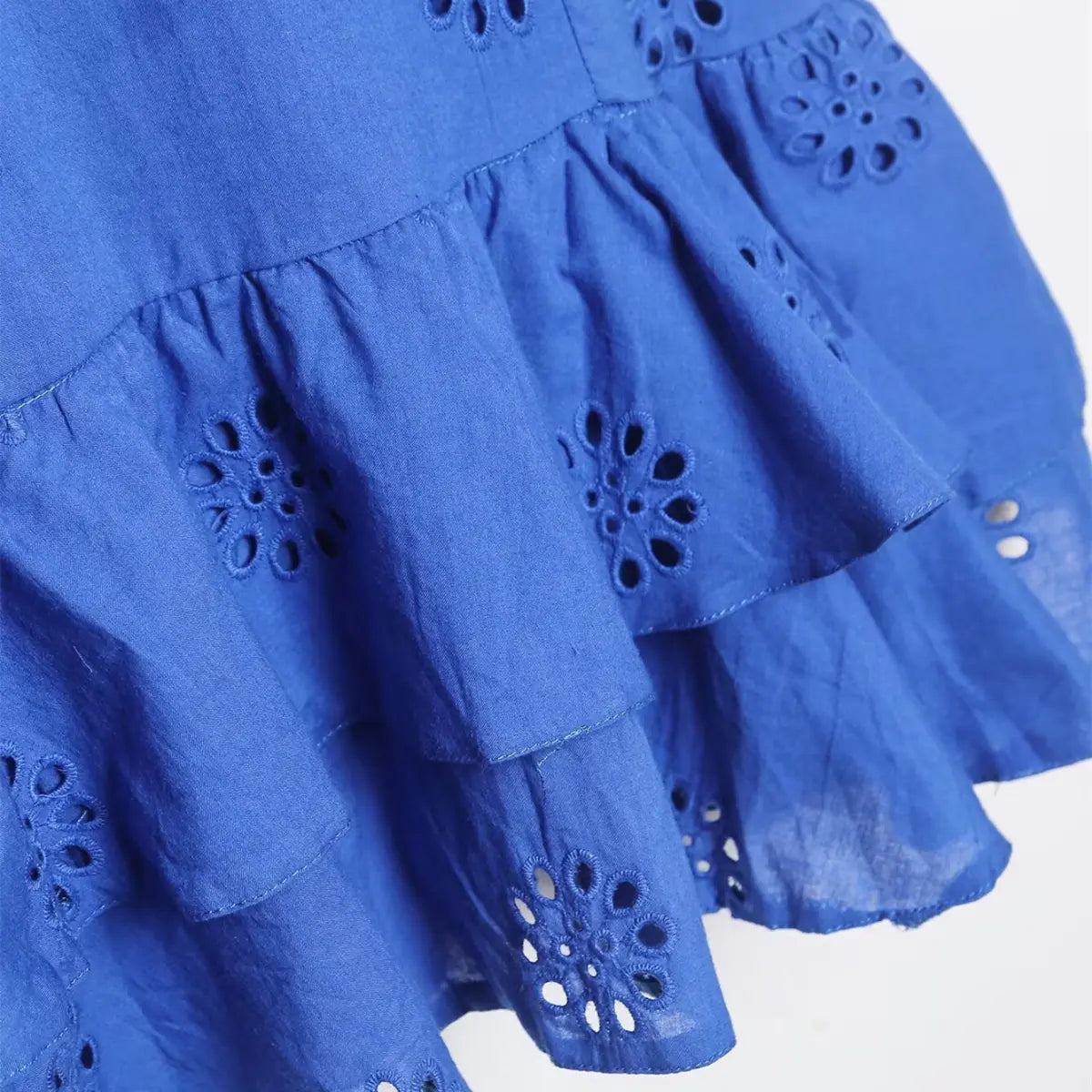 Skirt detail of royal blue eyelet ruffle dress, highlighting the floral cutwork embroidery and gathered tiered layers
