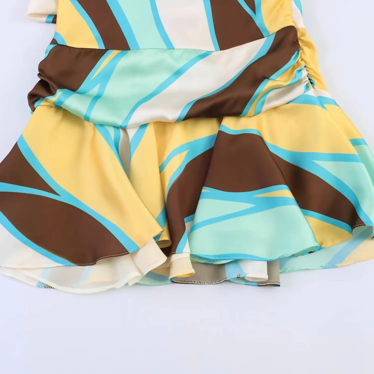 Close‑up of layered ruffle hem, abstract geometric print mini dress