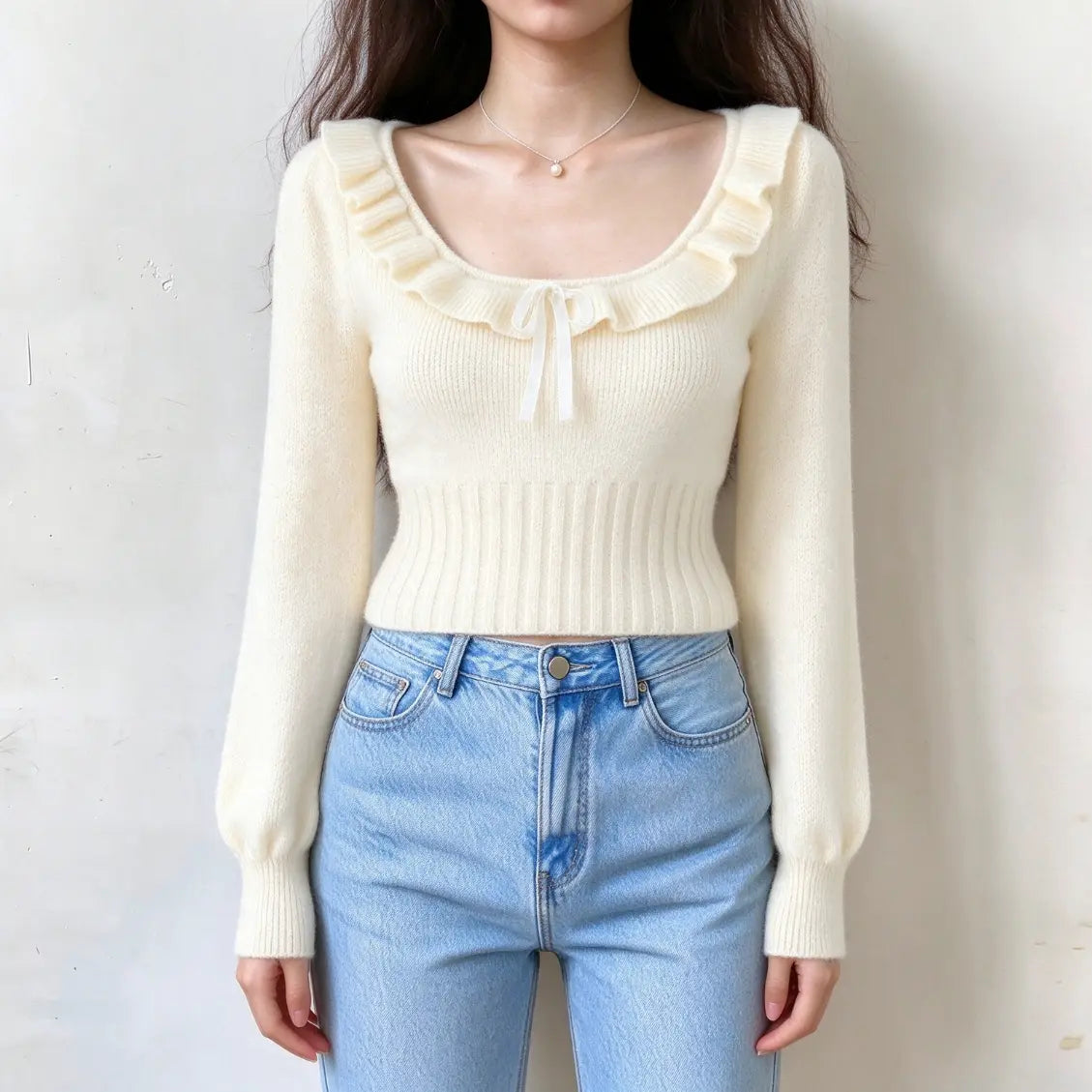 Model wearing ruffle trim satin bow fuzzy knit cropped sweater with jeans, front view