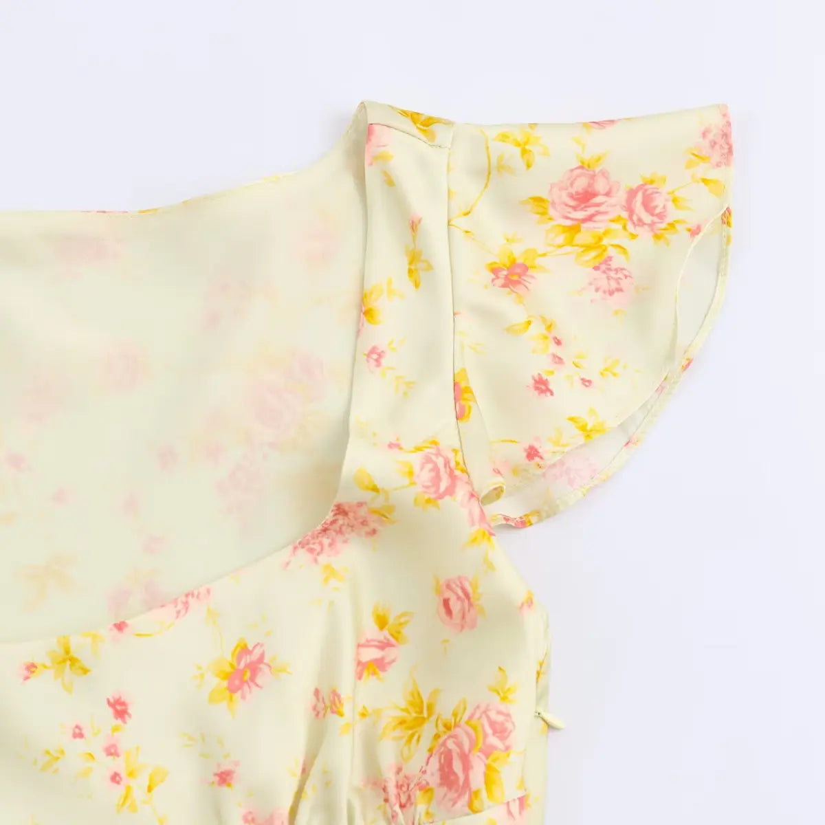 Close-up of the ruffled cap sleeve on a pale yellow floral dress, highlighting the fluttery edge.