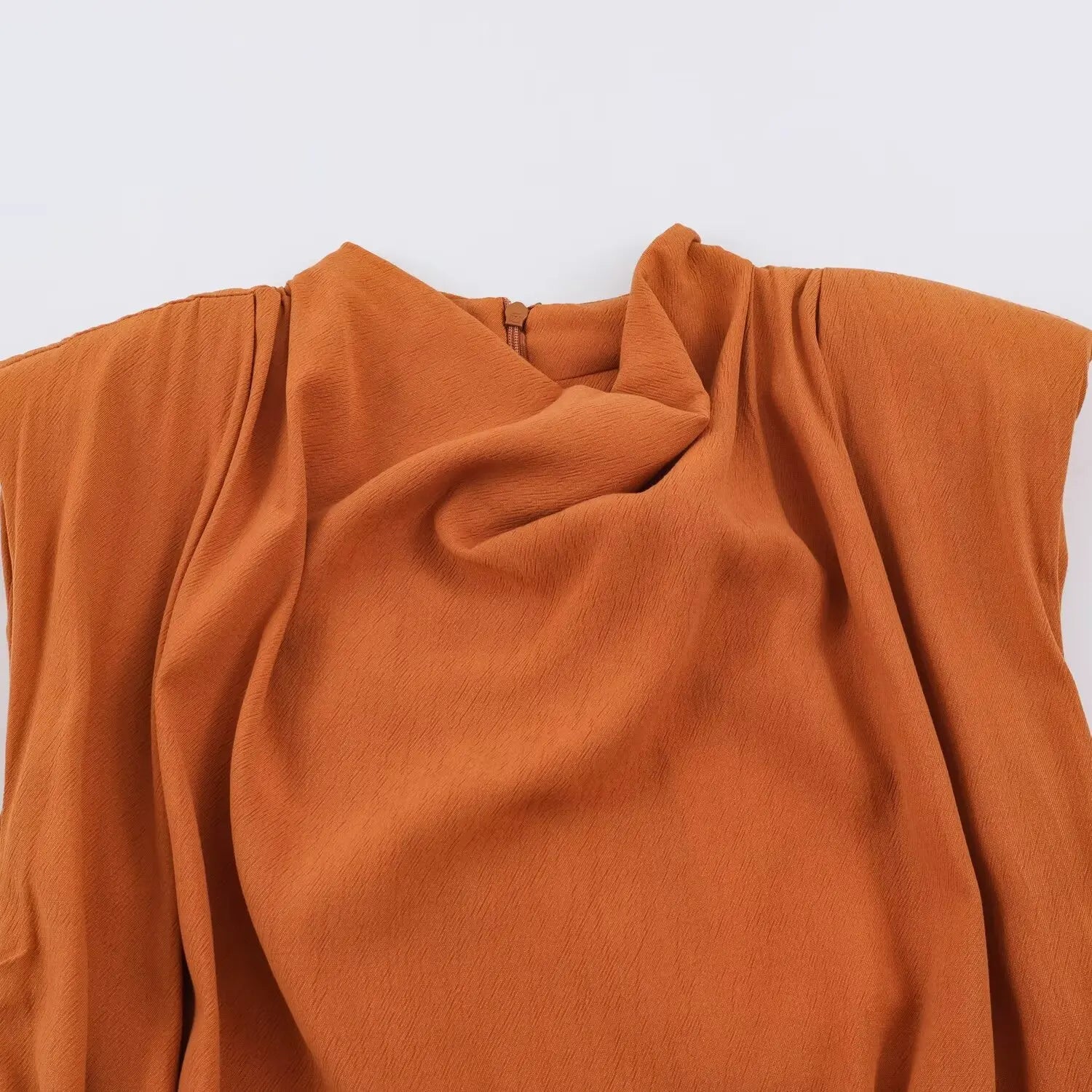 Close-up of cowl drape neckline on rust brown sleeveless romper, natural draped front folds, back zipper detail