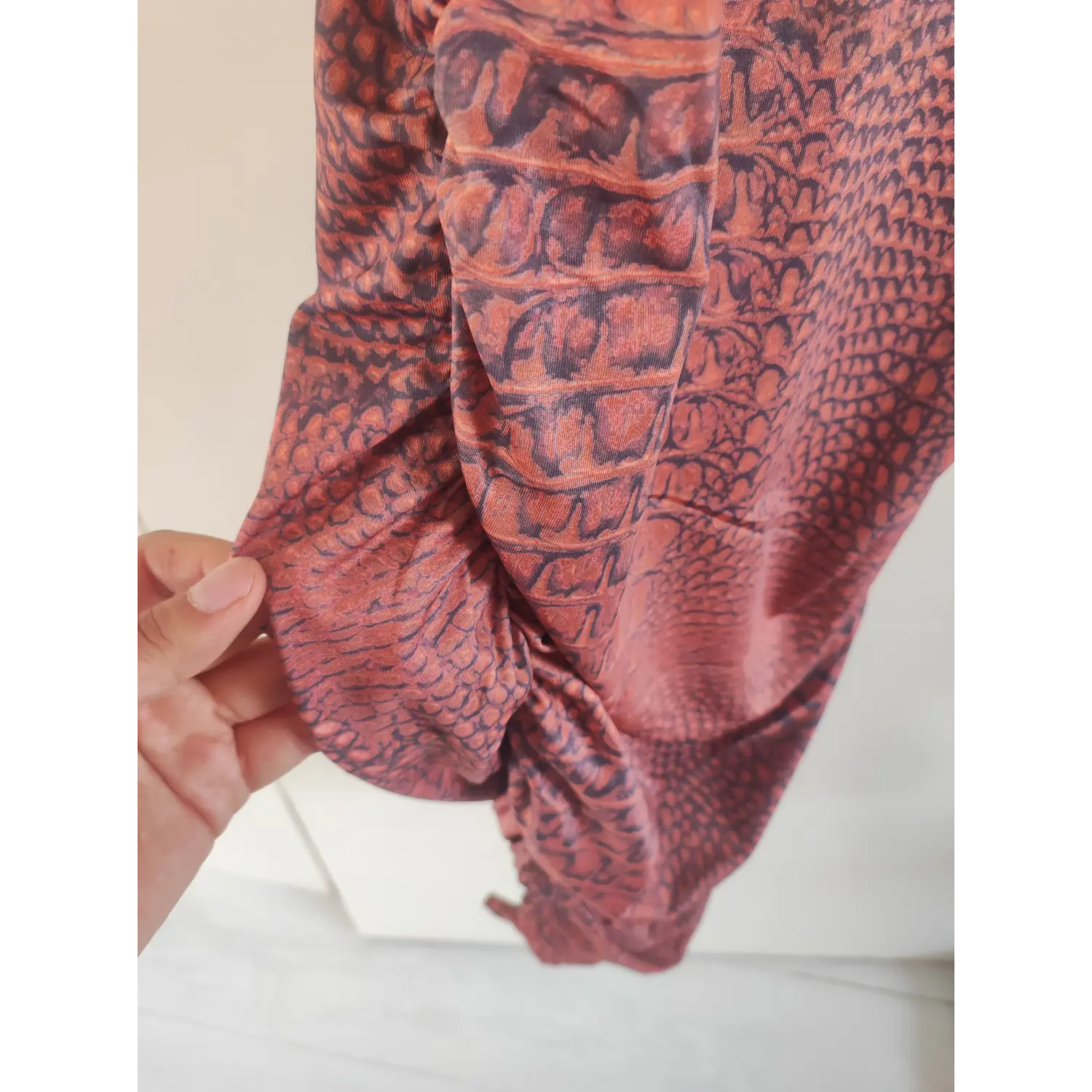 fabric-detail-view | Close-up of crocodile scale printed stretch fabric, side ruched stitching of bodycon midi dress