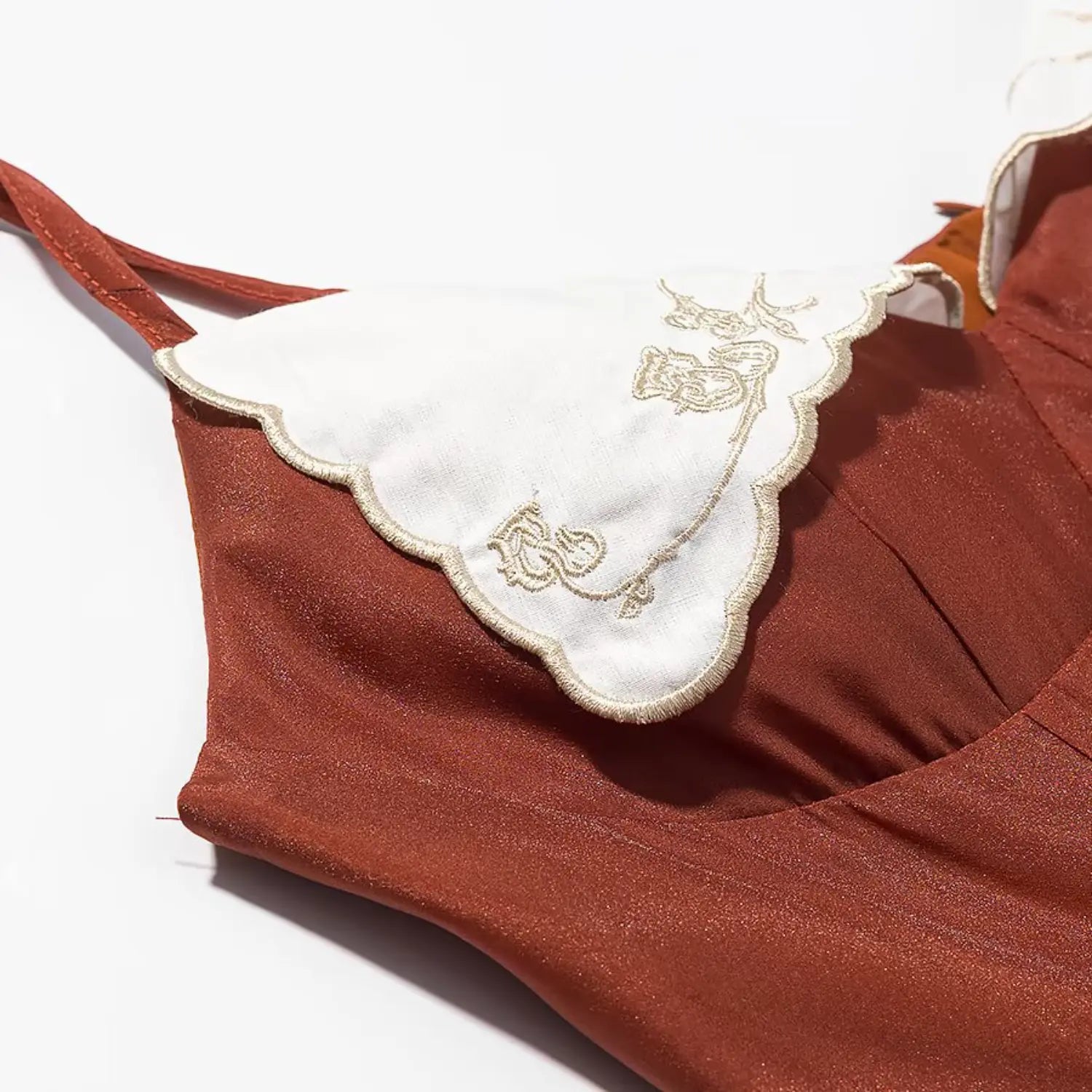 Extreme close‑up of golden floral embroidery and scalloped edge on white lace collar