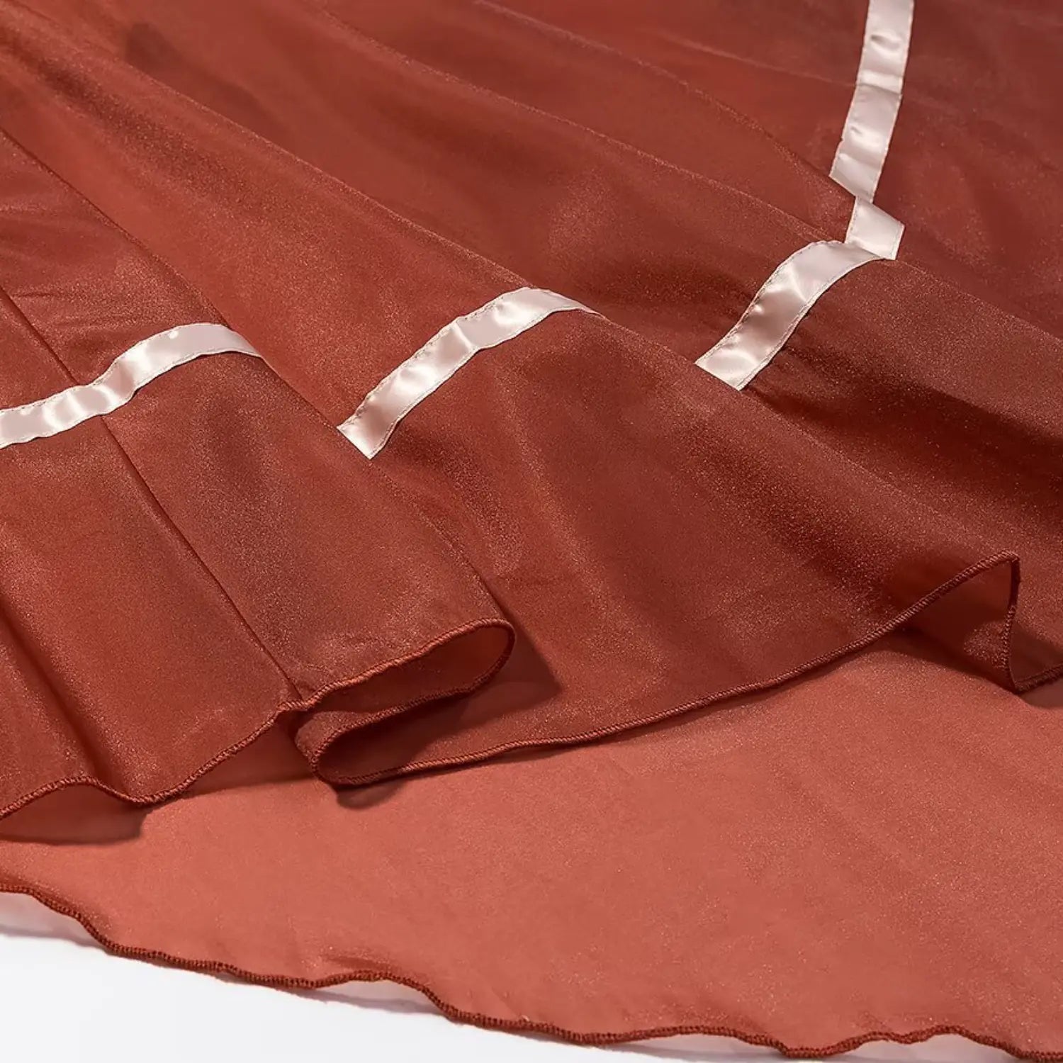 Close‑up layered view of asymmetrical handkerchief hem and satin ribbon trim on chiffon skirt