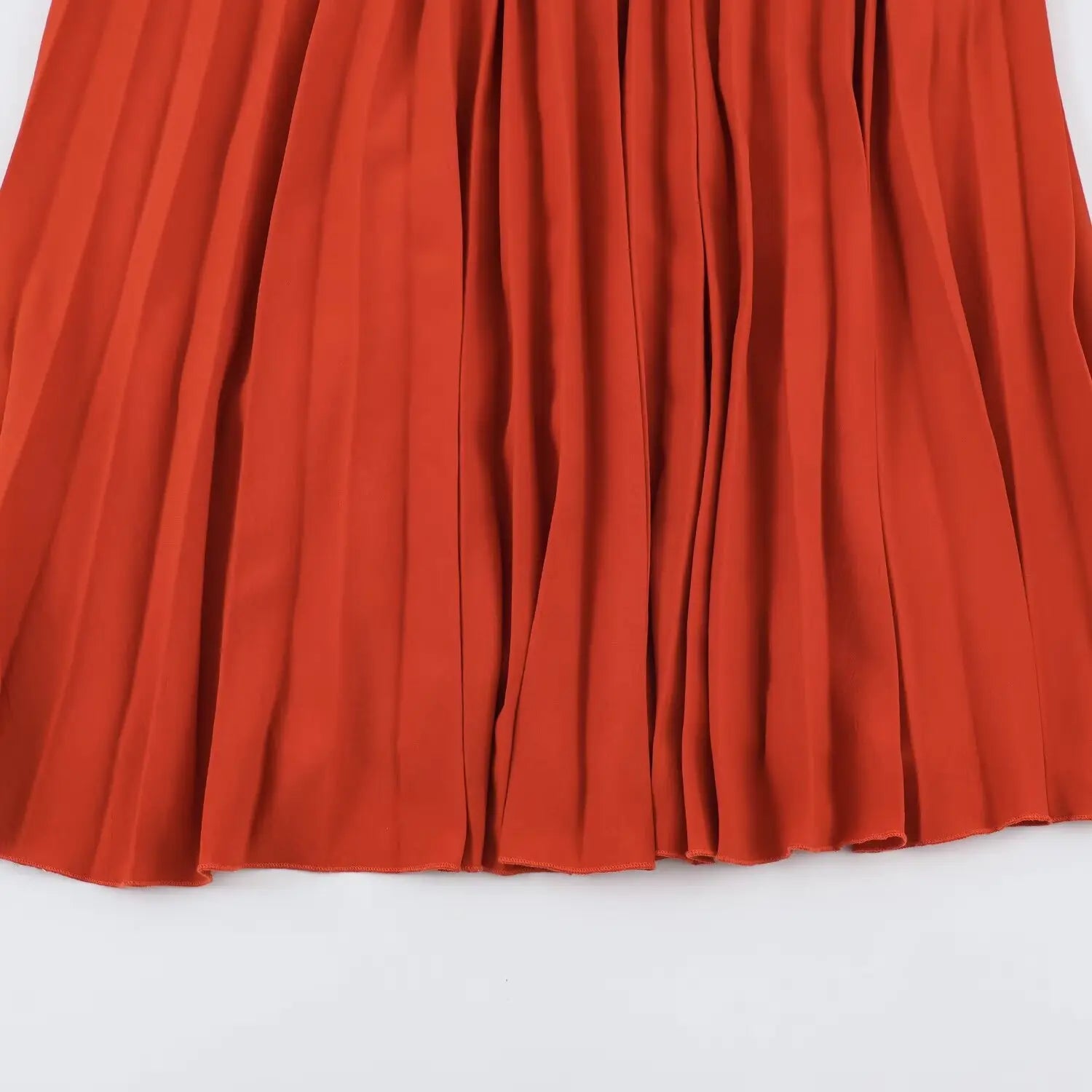 Flat closeup of rust orange sharp vertical pleated chiffon fabric, flowing skirt hem texture