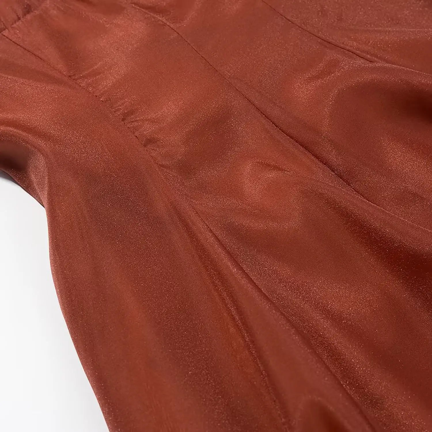 Close‑up texture shot of shimmer rust orange chiffon fabric with vertical garment seams