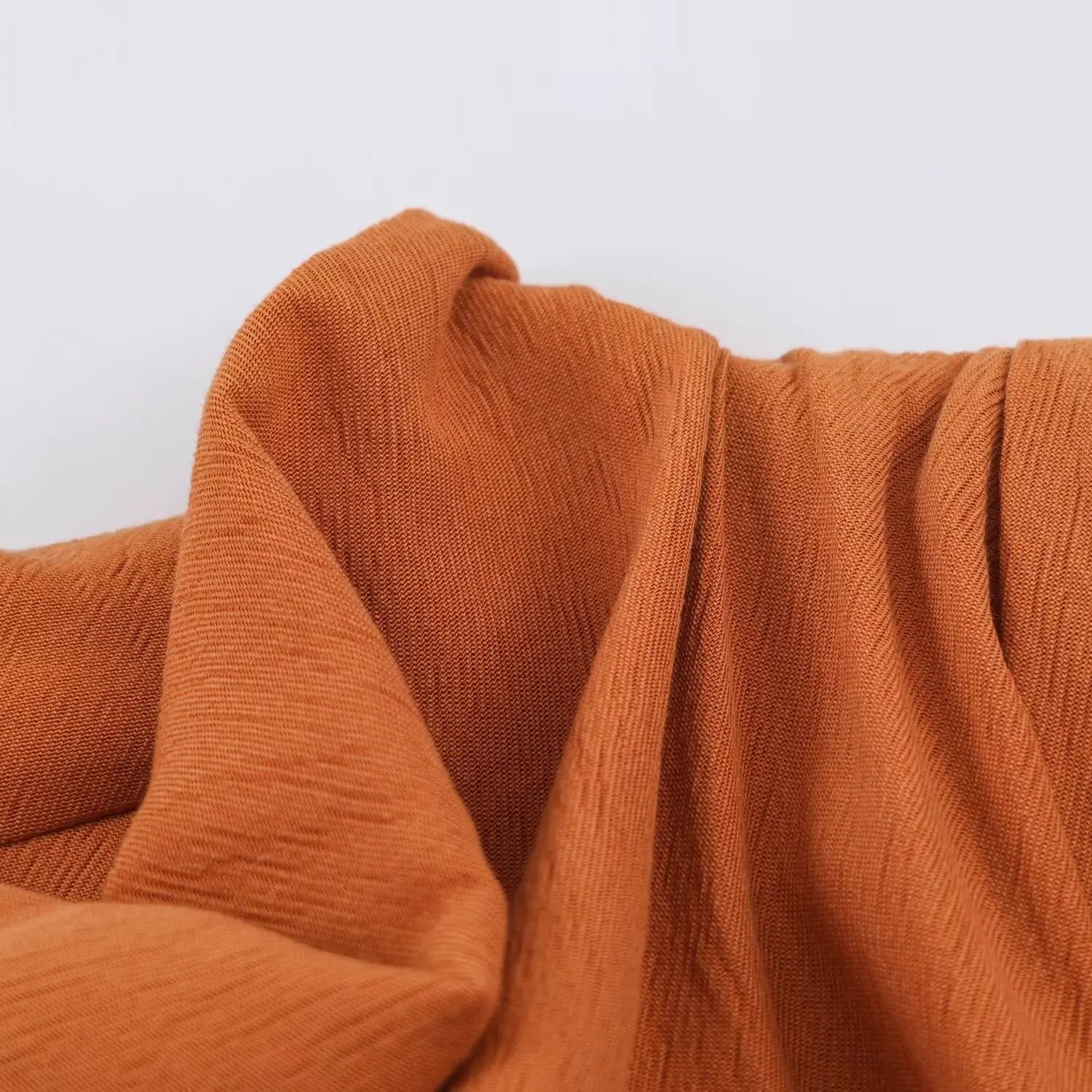 Fabric drape close-up, soft flowing texture of rust textured woven playsuit material