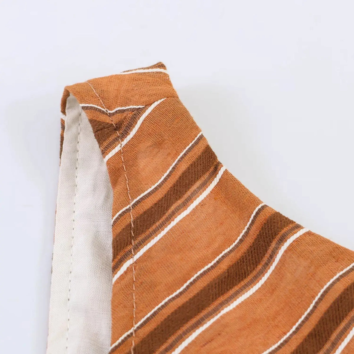 Macro shot of rust stripe maxi dress shoulder seam, textured woven fabric and neat stitching