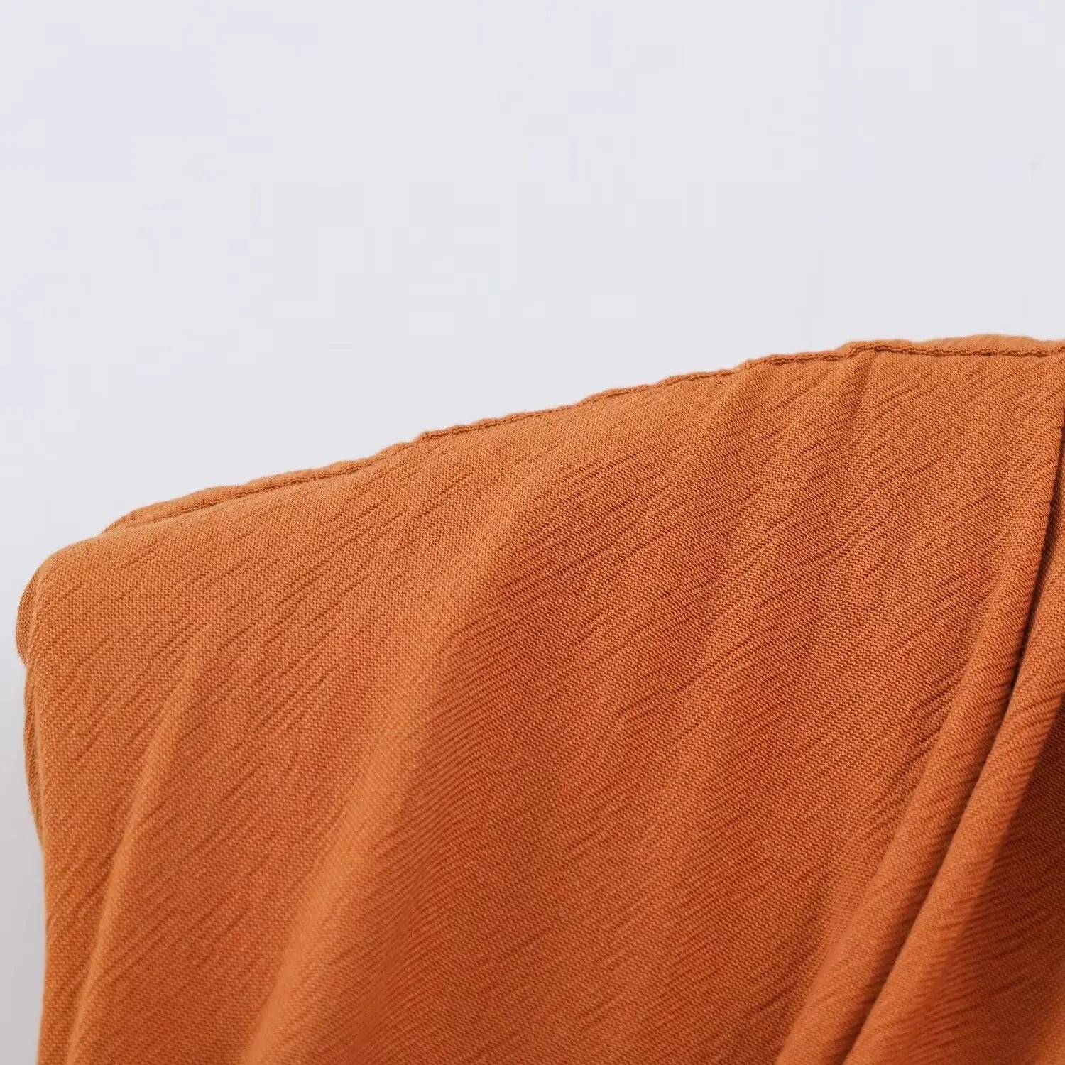 Macro texture shot of lightweight rust brown crinkle woven fabric, fine vertical wrinkle texture