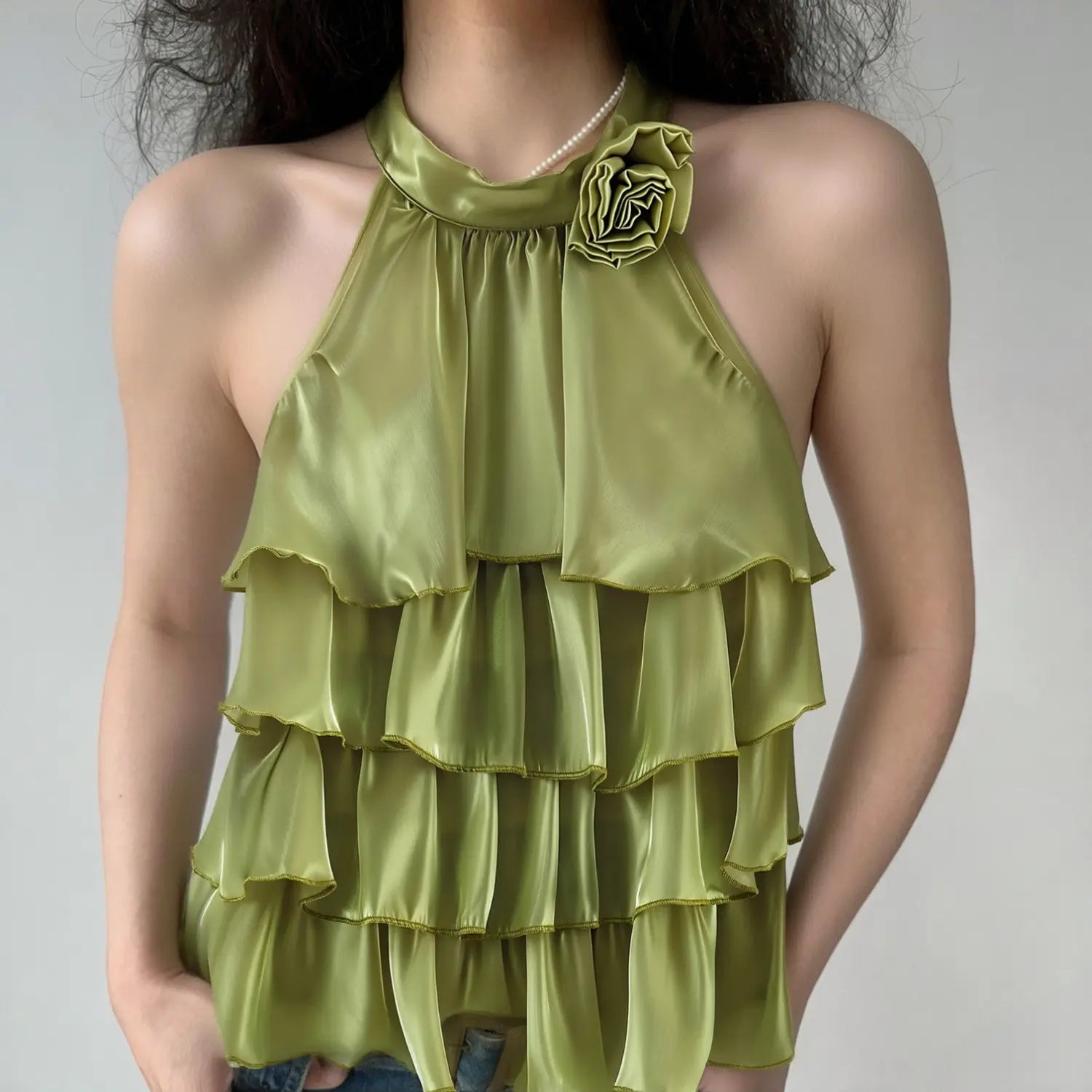 Lifestyle model shot sage green halter sleeveless top, 3D fabric rose decor, multi layered tiered ruffle hem, shiny organza fairy blouse