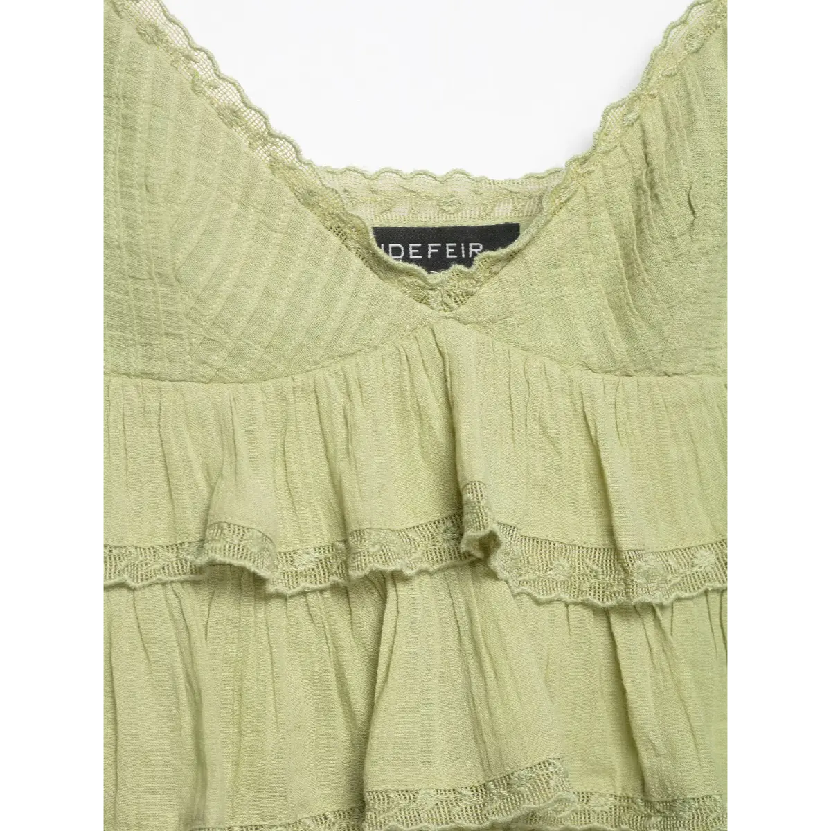 Close-up of the cami top's front neckline, featuring lace trim, stitched bodice, and tiered ruffles.