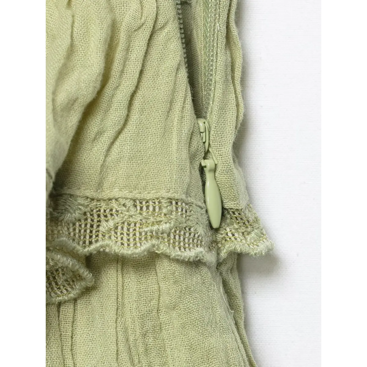 Close-up of the cami top's side zipper, with a matching sage-green pull tab.
