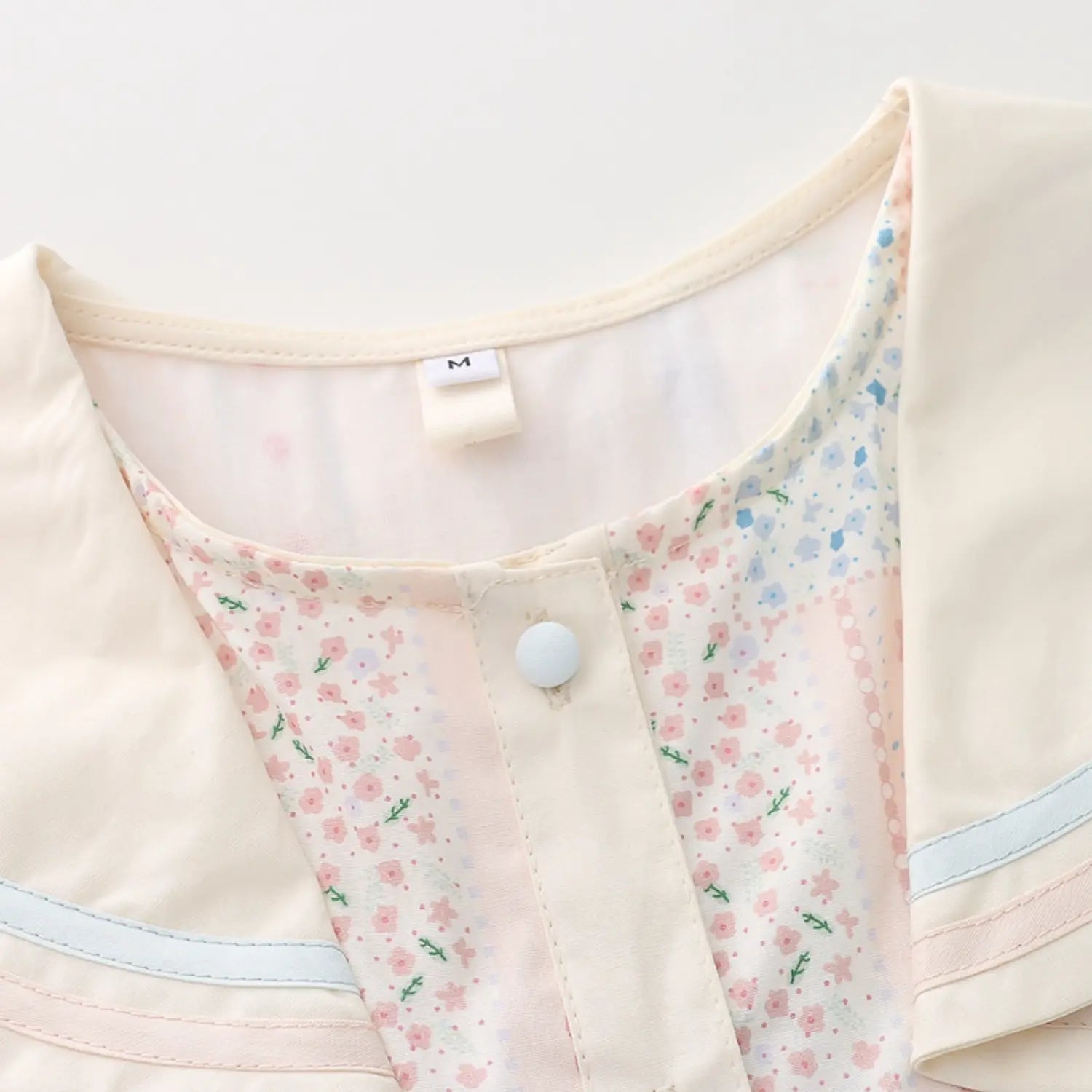 Sailor collar placket white round button macro close-up, matte cream resin buttons double secure stitching double blue pink piping trim on lapel edge neat placket binding craft shot