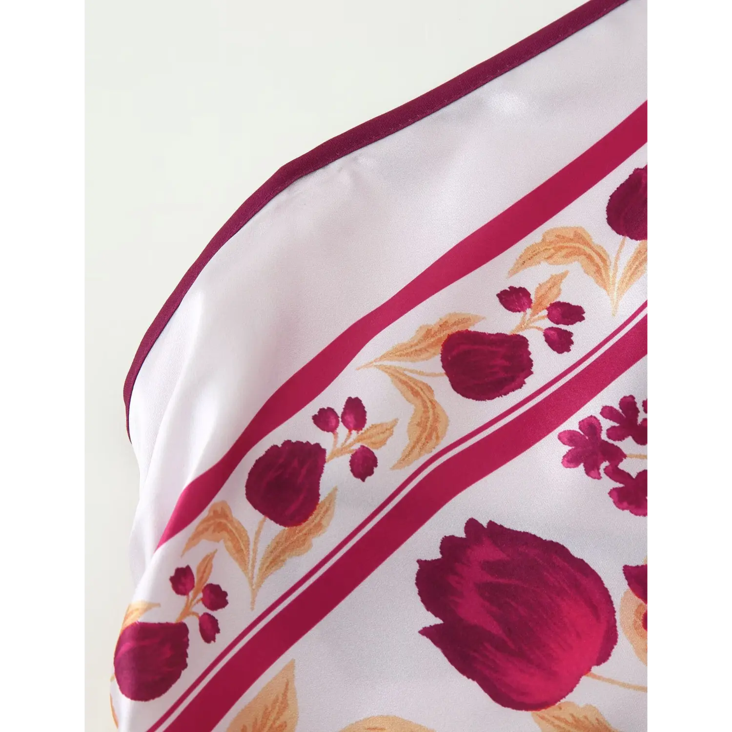 Close‑up of satin fabric, burgundy floral border print, smooth shiny textile texture