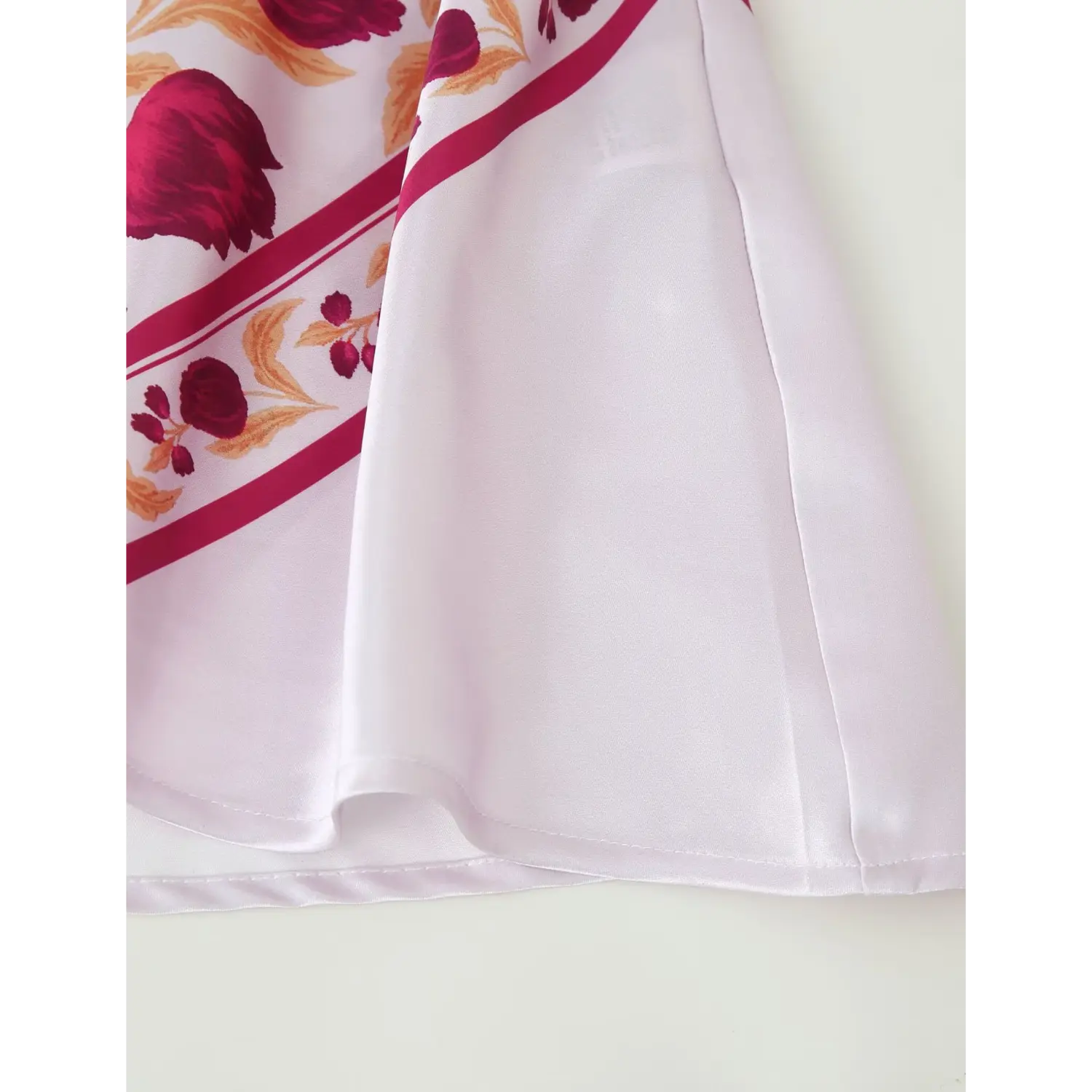 Close‑up of satin maxi dress mermaid hem, finished stitching, smooth white satin fabric edge