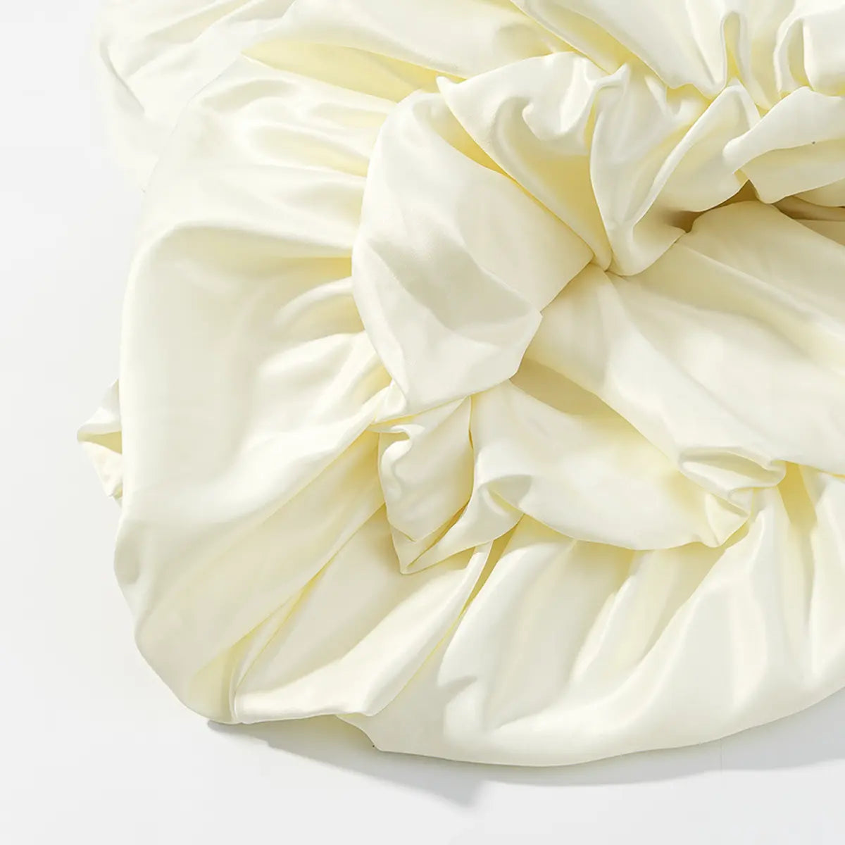 Close-up of the satin ruffle fabric on a cream halter dress, showing the sheen, drape, and gathered construction.