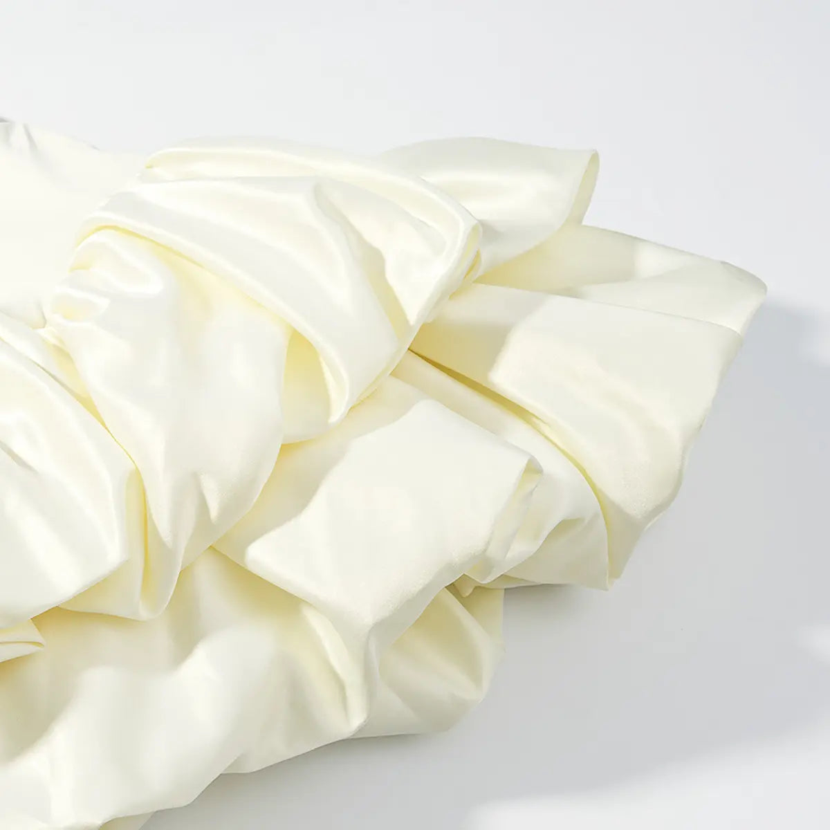 Close-up of the satin ruffled hem on a cream halter dress, highlighting the smooth, lustrous texture and gathered construction.